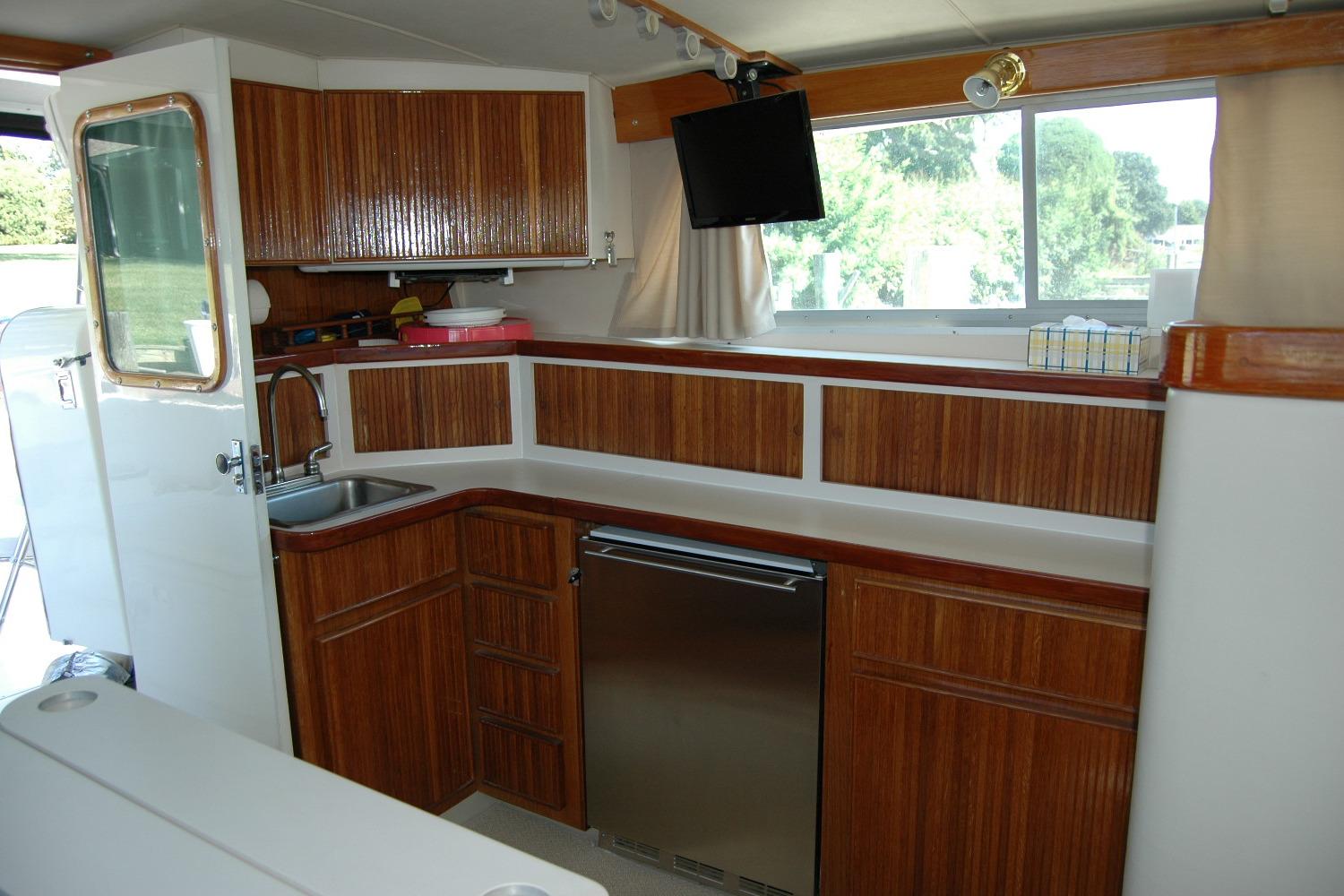 1987 Bertram 33 Sport Fisherman interior with wood cabinetry and stainless steel appliances.