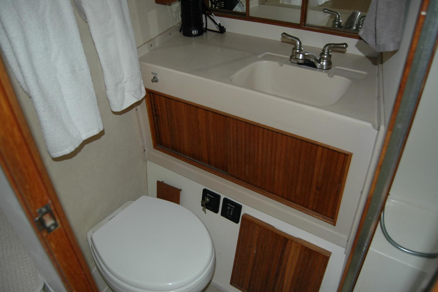 1987 Bertram 33 Sport Fisherman bathroom with sink, toilet, and wooden cabinetry.