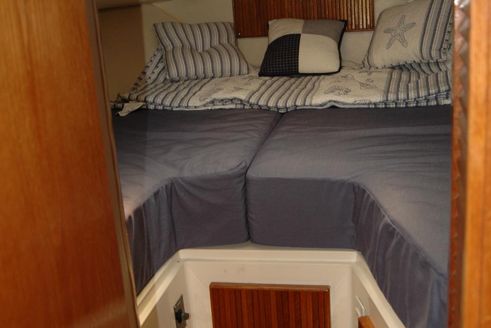 Cozy cabin interior of 1987 Bertram 33 Sport Fisherman with striped bedding and pillows.