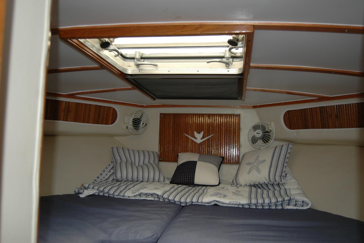 Interior cabin of 1987 Bertram 33 Sport Fisherman with cozy bedding and ceiling hatch.