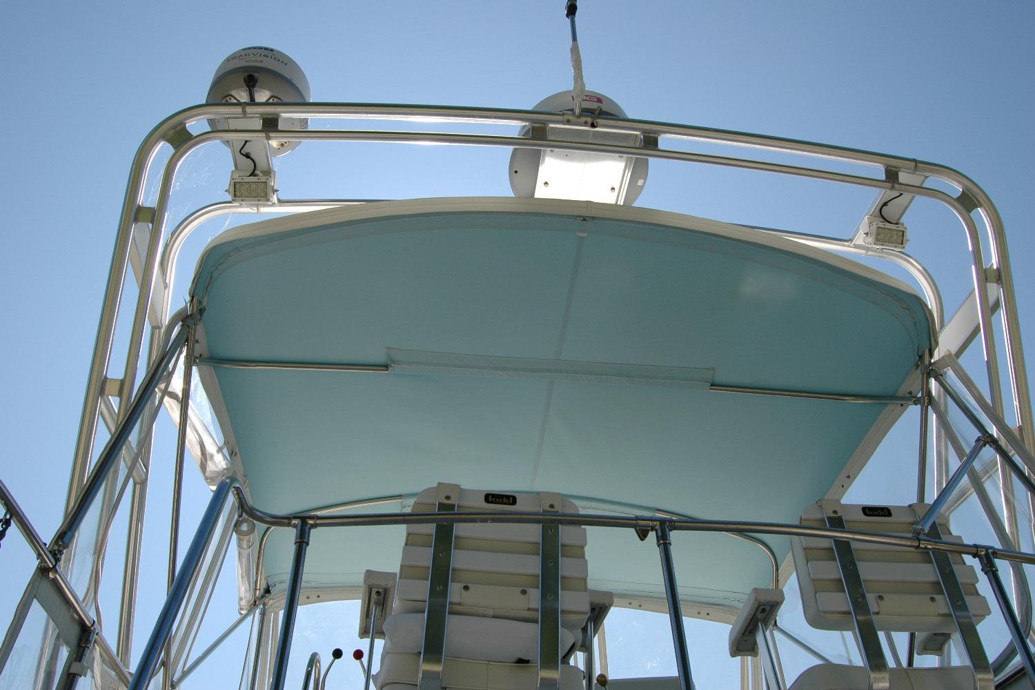 1987 Bertram 33 Sport Fisherman boat, view of upper deck and equipment against clear sky.