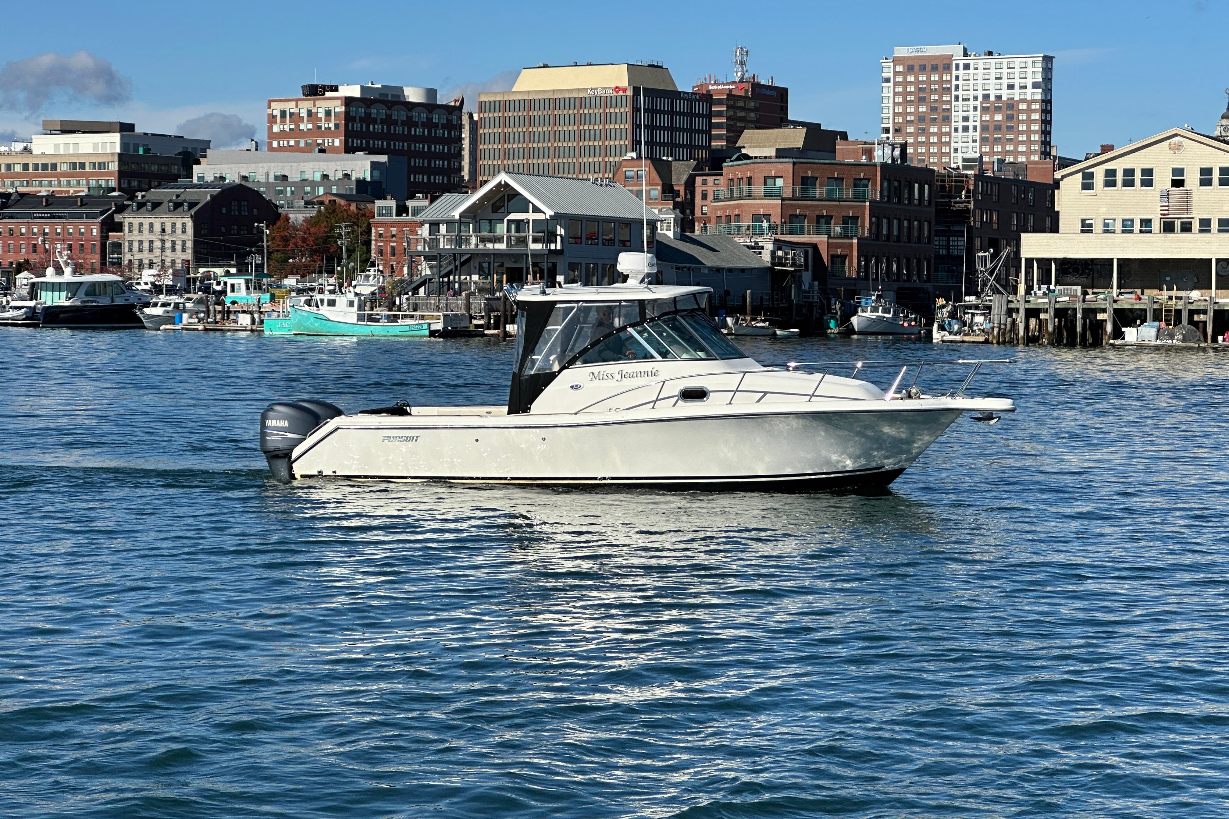 2007 Pursuit OS 285 Offshore boat cruising in urban harbor with cityscape backdrop.