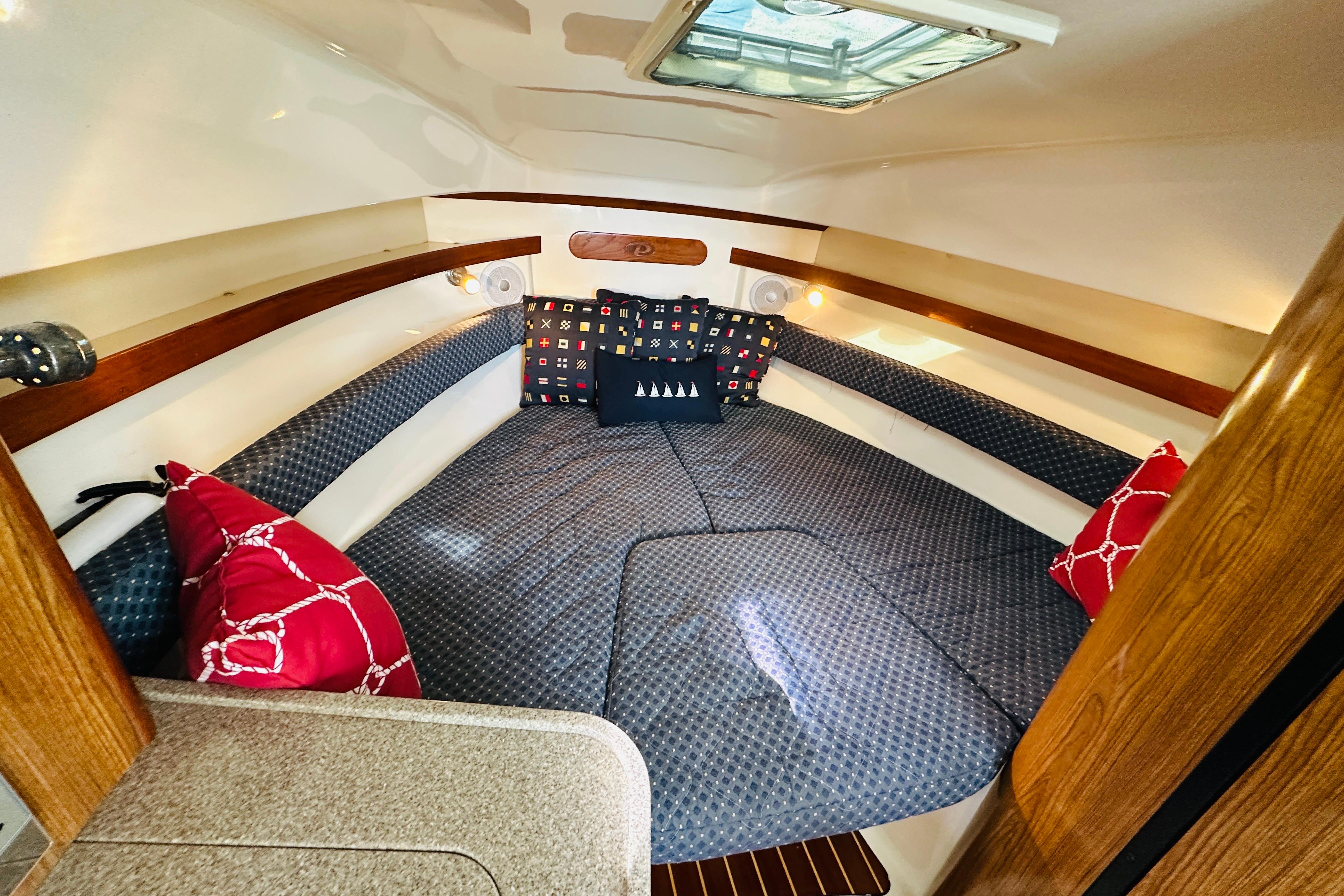 Cozy cabin interior of 2007 Pursuit OS 285 Offshore with patterned cushions and pillows.