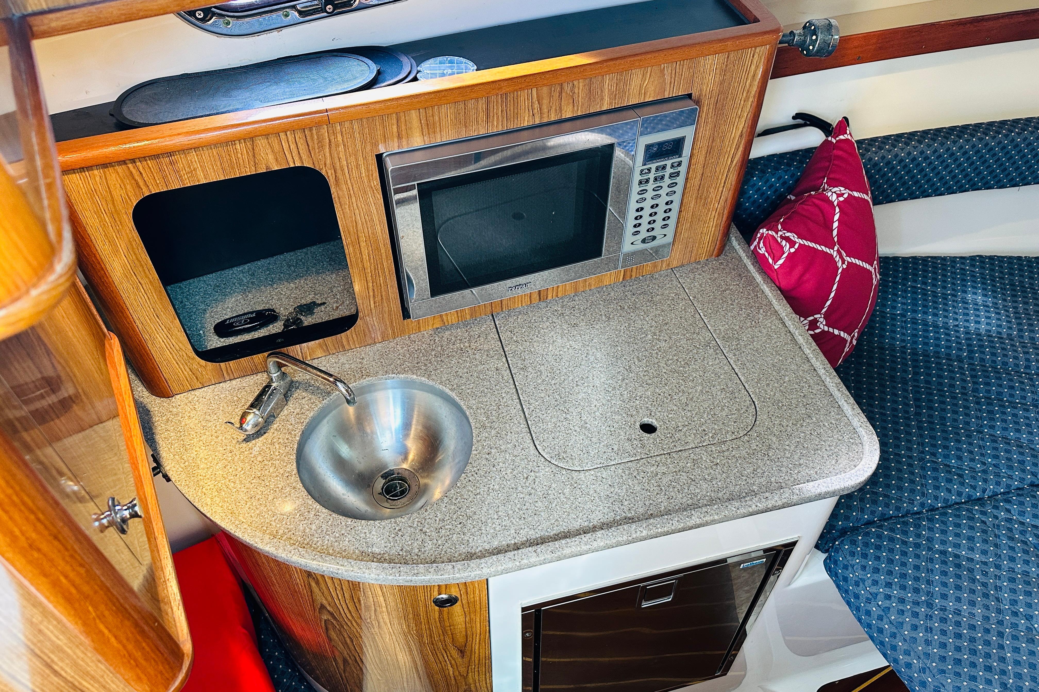 Compact galley in 2007 Pursuit OS 285 Offshore boat with sink, microwave, and seating.