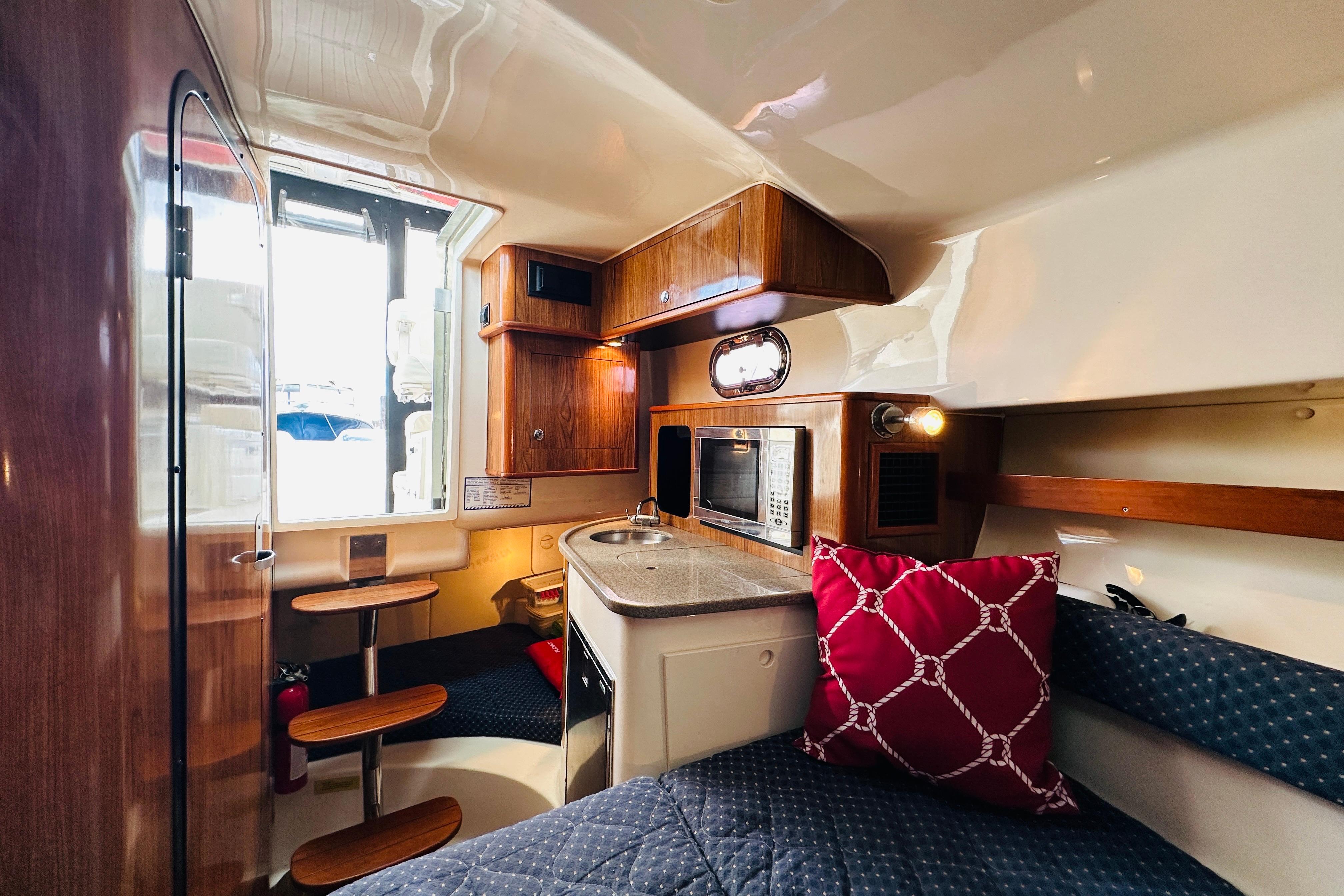 2007 Pursuit OS 285 Offshore cabin interior with kitchenette, seating, and wooden accents.