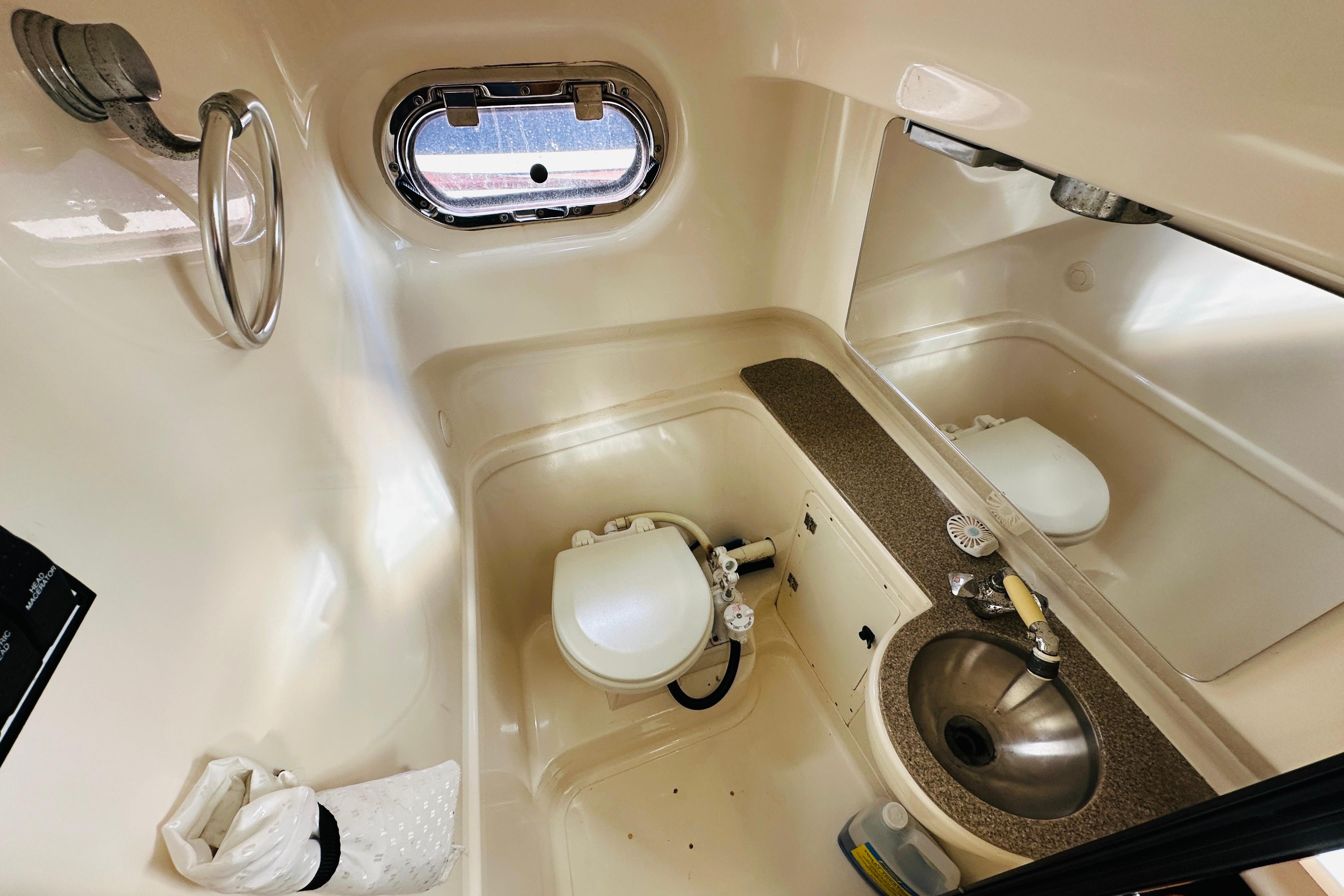 2007 Pursuit OS 285 Offshore boat bathroom with sink, toilet, and porthole window.
