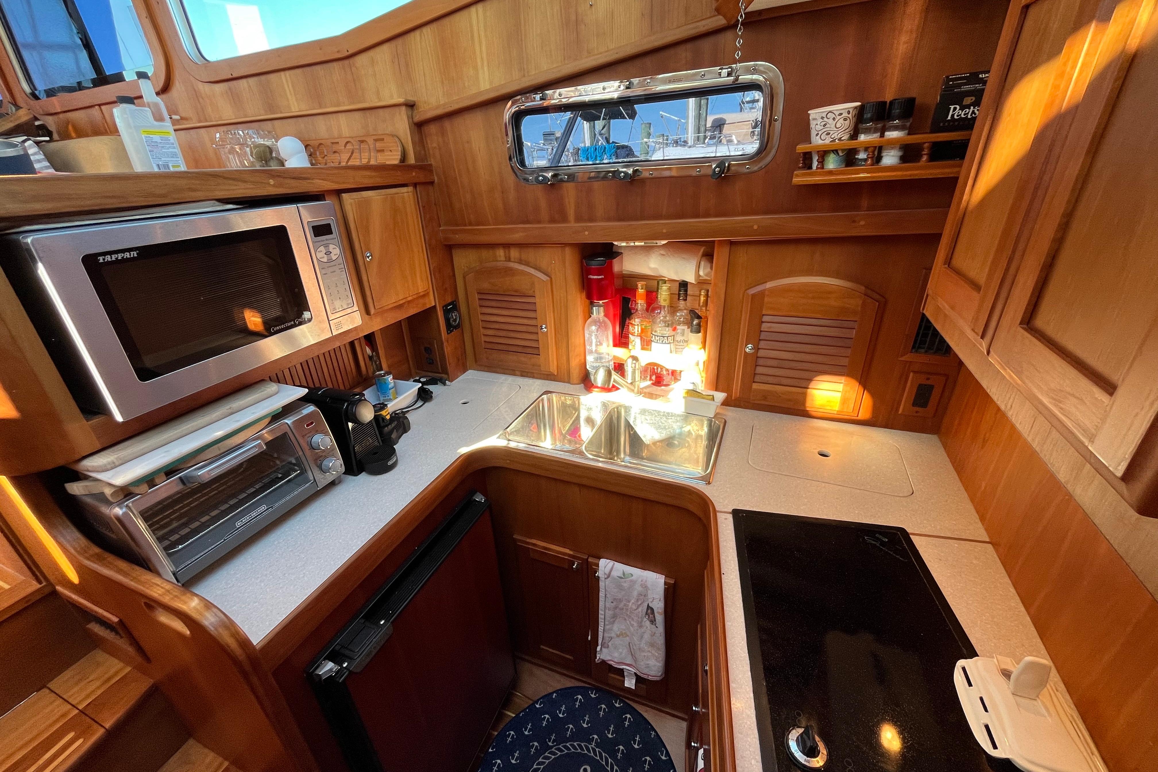 2006 Sabre 36 Flybridge Sedan kitchen with microwave, sink, and wooden cabinetry.
