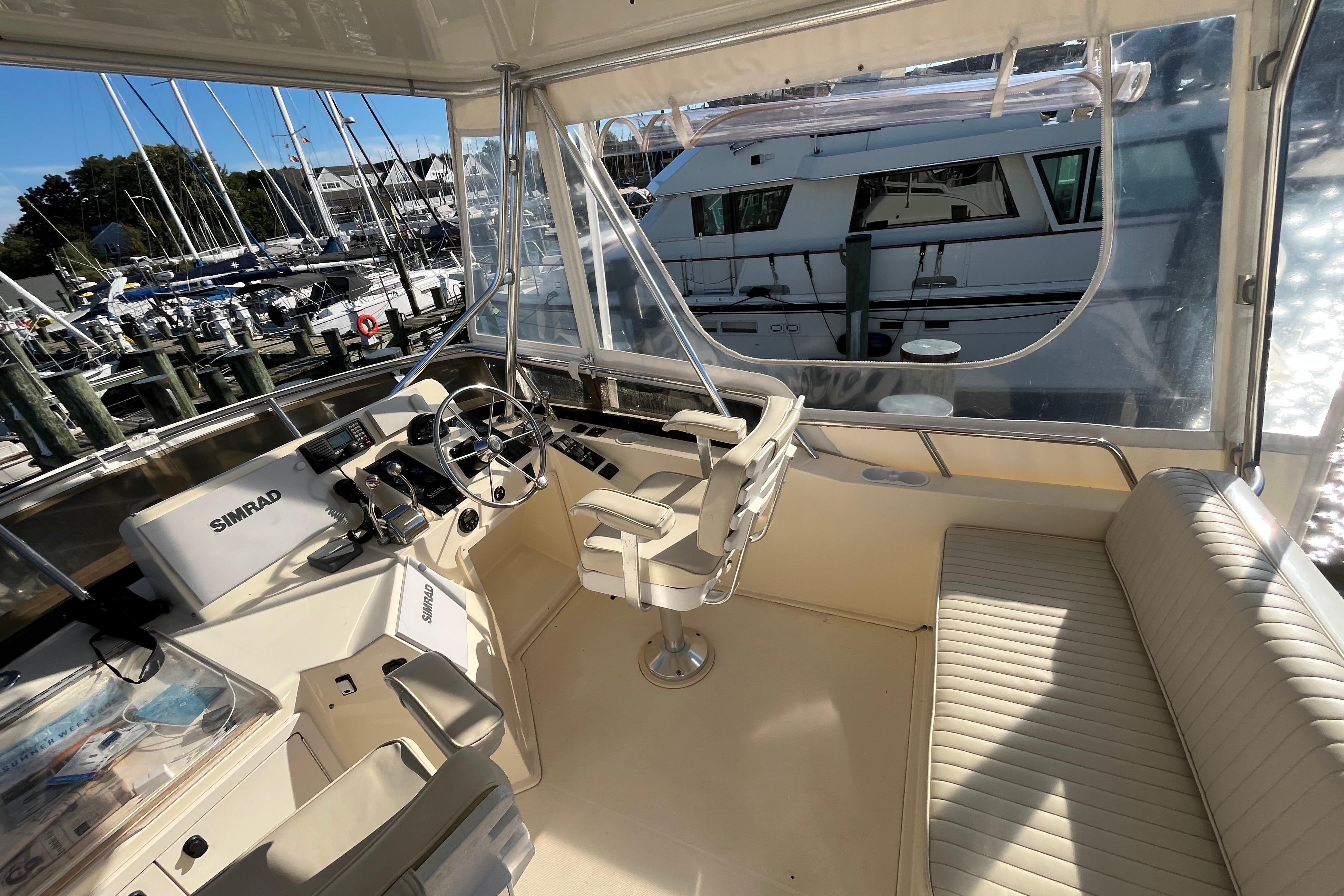 2006 Sabre 36 Flybridge Sedan helm with Simrad navigation, docked at marina.