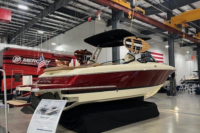 2026 Chris-Craft Sportster 28 boat displayed indoors, featuring a sleek red and cream design.