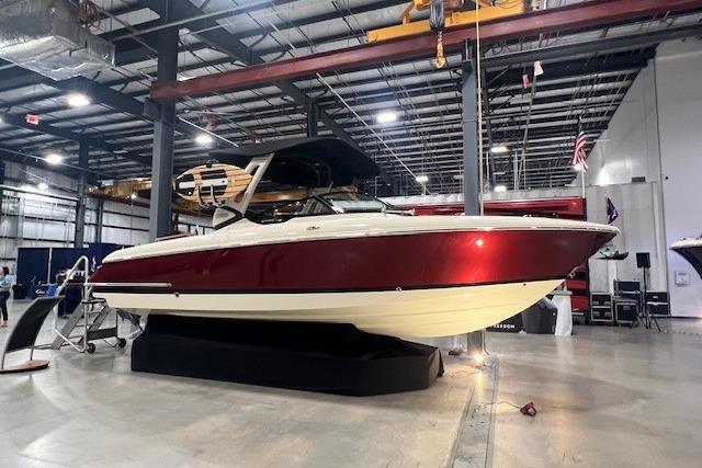 2026 Chris-Craft Sportster 28 boat displayed indoors, featuring sleek red and white design.