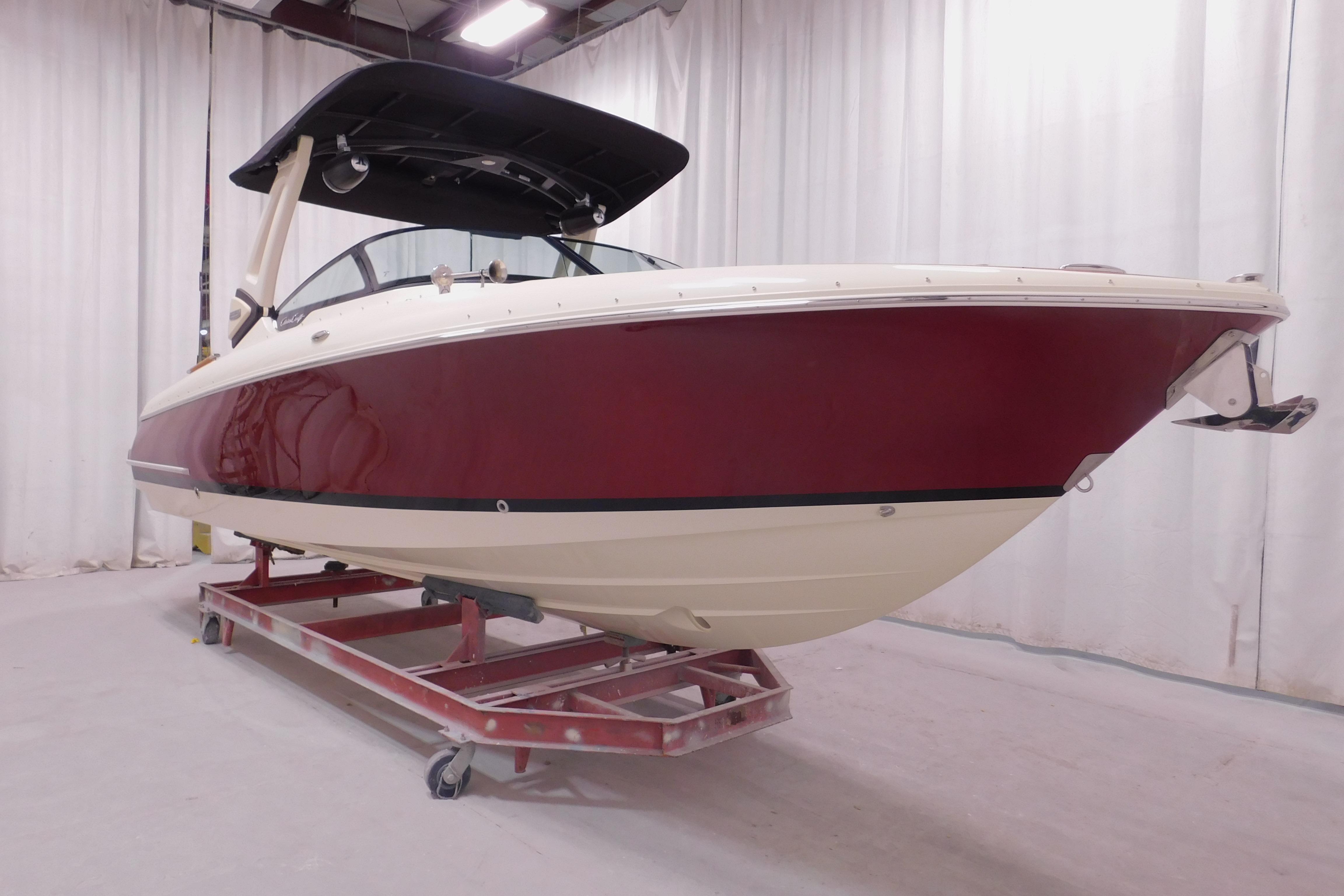 2026 Chris-Craft Sportster 28 boat with red hull in indoor showroom.