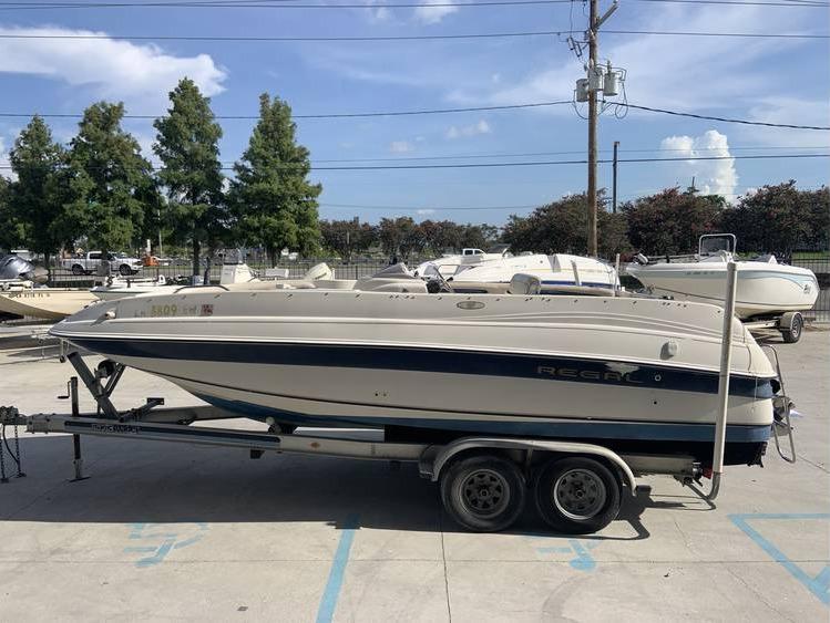 1997 Regal 200 DESTINY boat on a trailer in a marina parking lot.