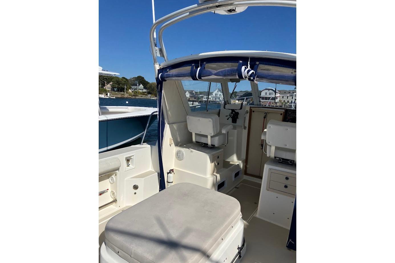2000 Albin 28 Tournament boat interior with seating and helm, docked by waterfront homes.