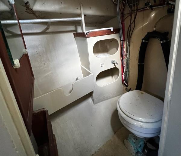 1974 Dyer 29' Sport Fisher boat bathroom with toilet and storage shelves.