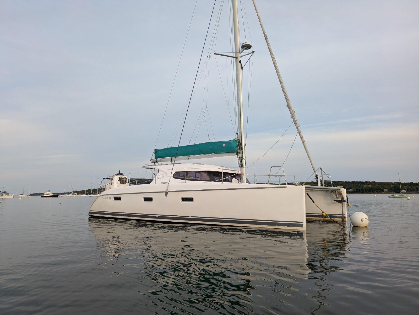 Nautitech 402 catamaran, 2011 model, anchored on calm water with a green sail cover.