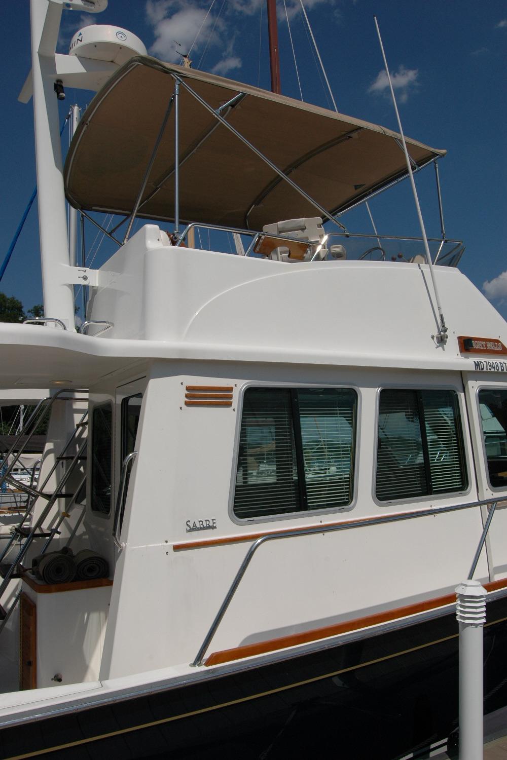 2006 Sabre 36 Flybridge Sedan yacht with canopy, docked under a clear blue sky.