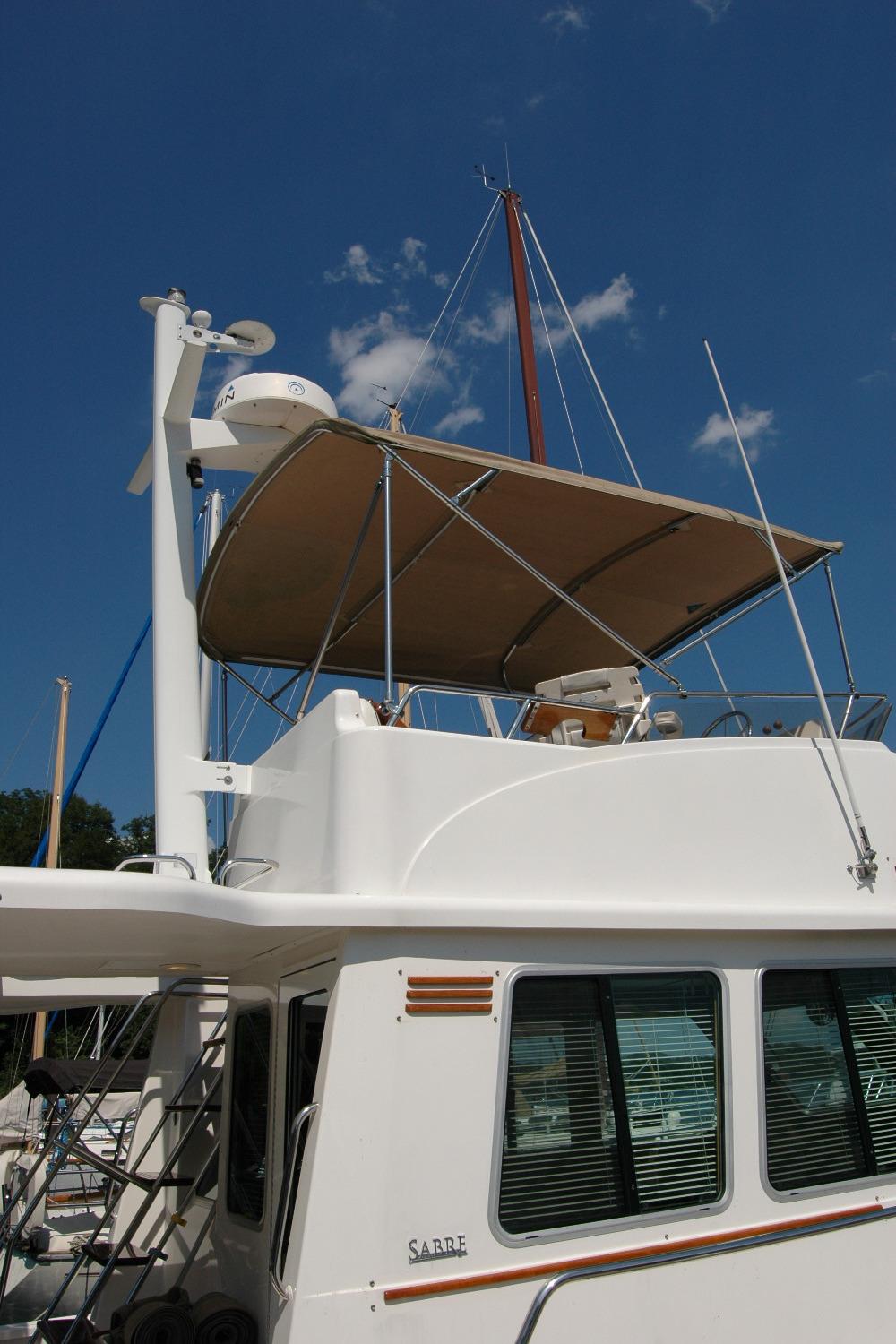 2006 Sabre 36 Flybridge Sedan with canopy, docked under clear blue sky.