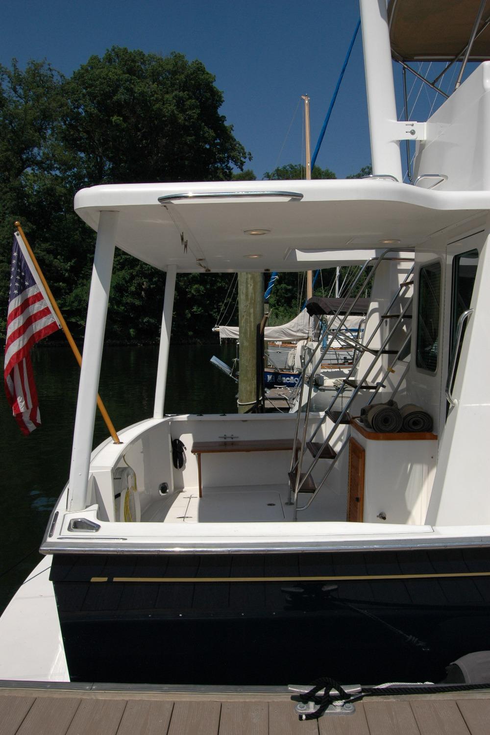 2006 Sabre 36 Flybridge Sedan docked, featuring spacious deck and American flag.