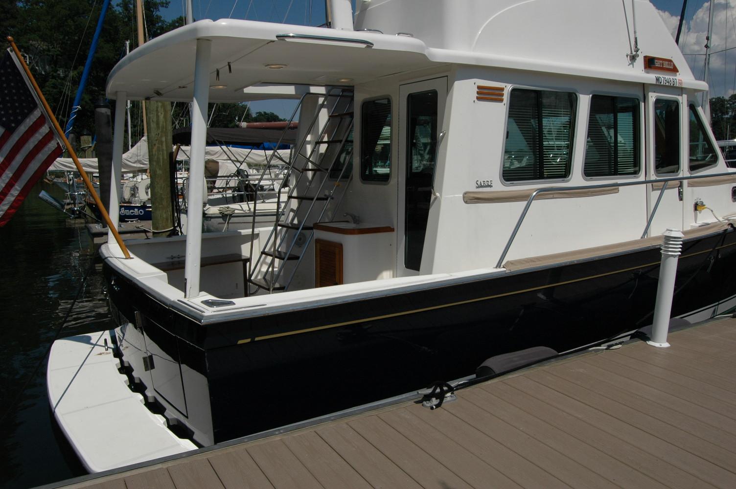 2006 Sabre 36 Flybridge Sedan docked, featuring sleek design and American flag.