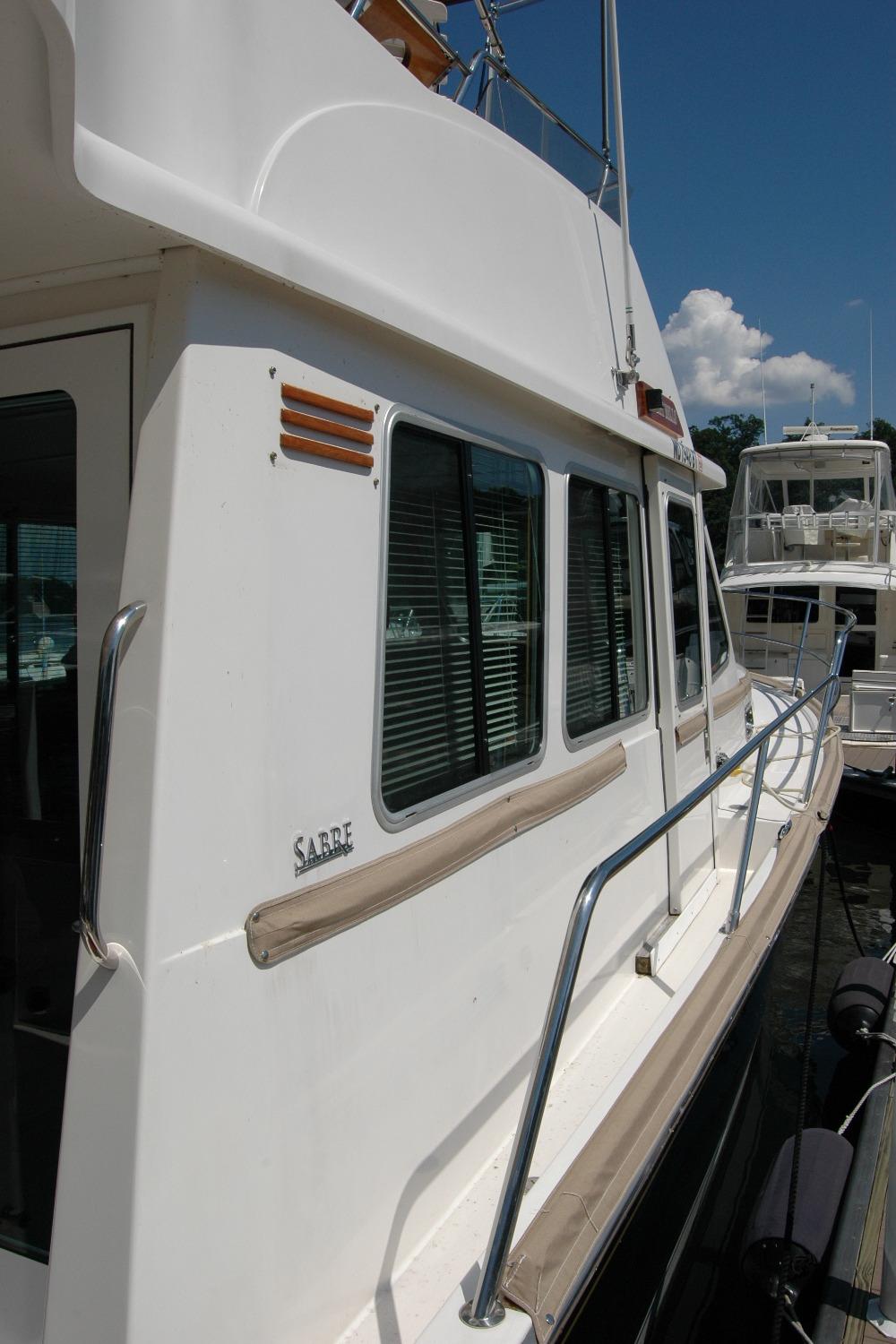 2006 Sabre 36 Flybridge Sedan yacht docked, showcasing sleek design and windows.