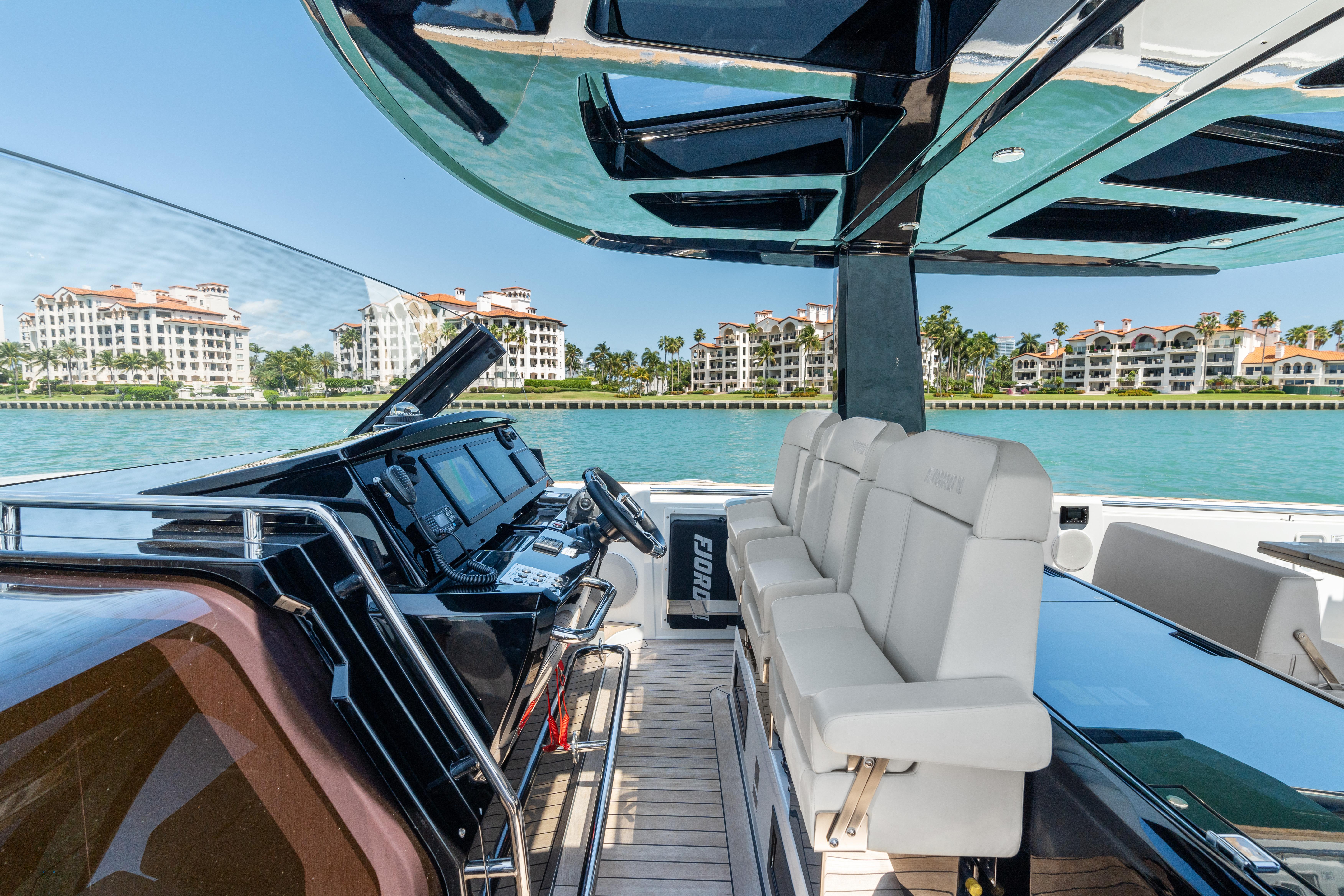 Fjord-44 Open 2022-HINJUICE FL-US-2022 Fjord 44 Open yacht interior with luxurious seating and modern controls, overlooking waterfront buildings.-9860902 | Thumbnail