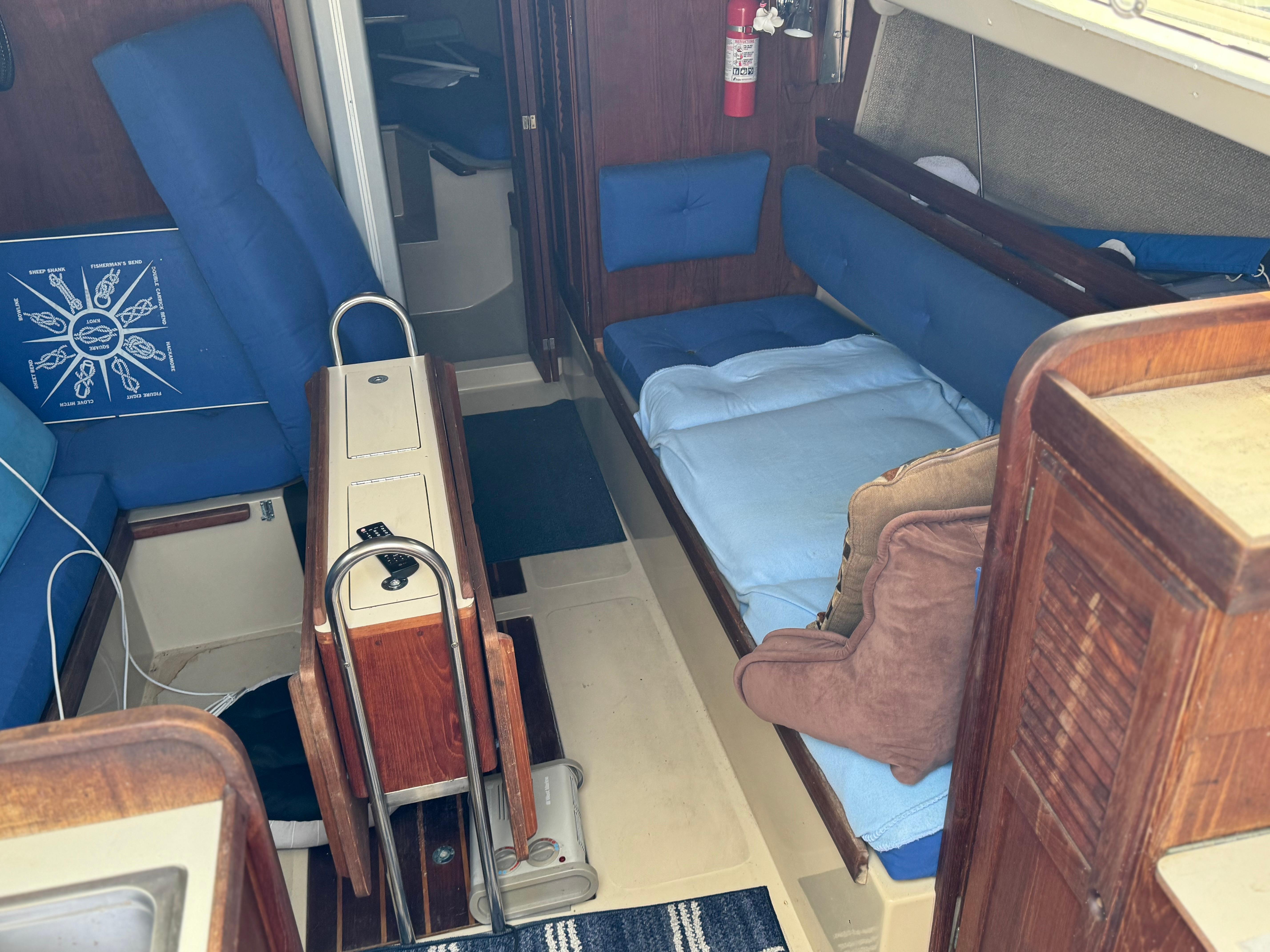 Interior of 1982 O'Day 34 sailboat with blue cushions and wooden cabinetry.