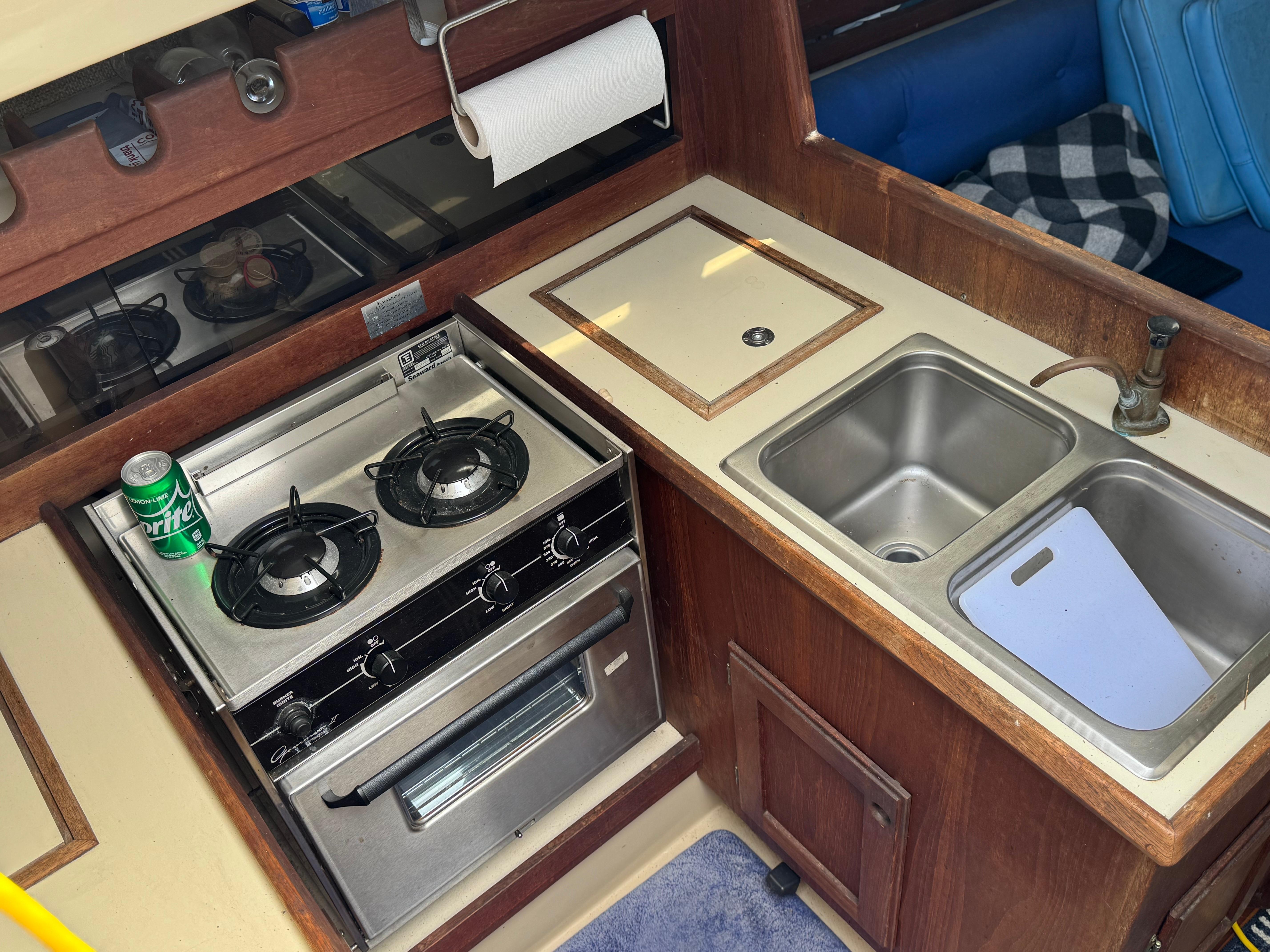 1982 O'Day 34 yacht kitchen with stove, double sink, and wooden cabinetry.