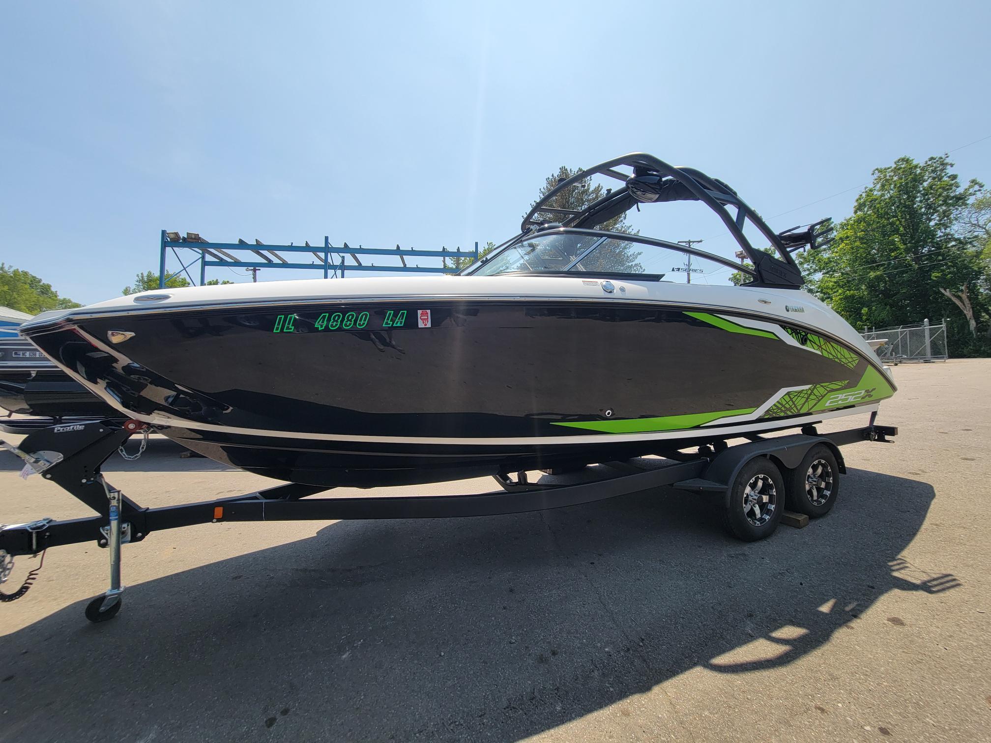 2021 Yamaha Boats 252XE on trailer, black and green design, parked outdoors.