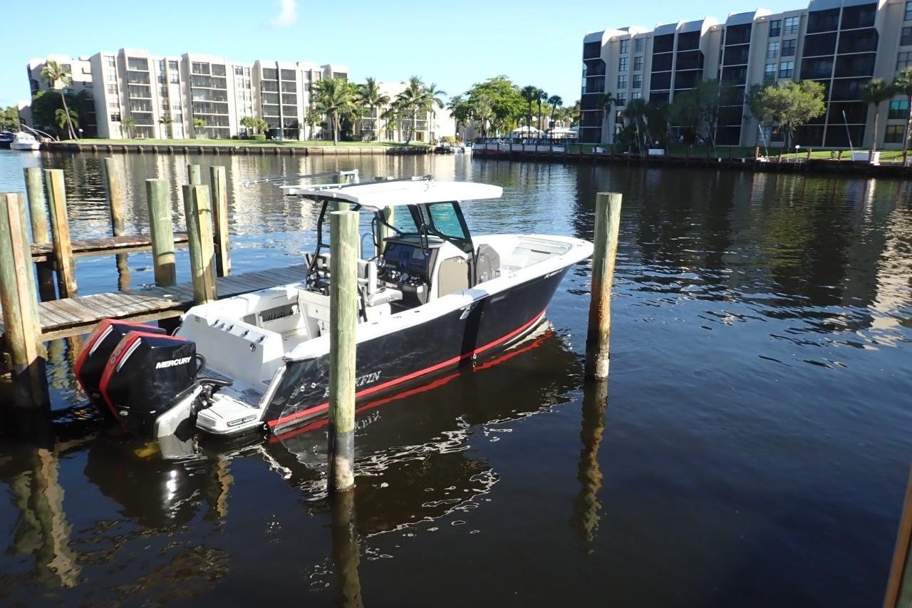 2022 Blackfin 272 CC boat docked in a marina with waterfront buildings.