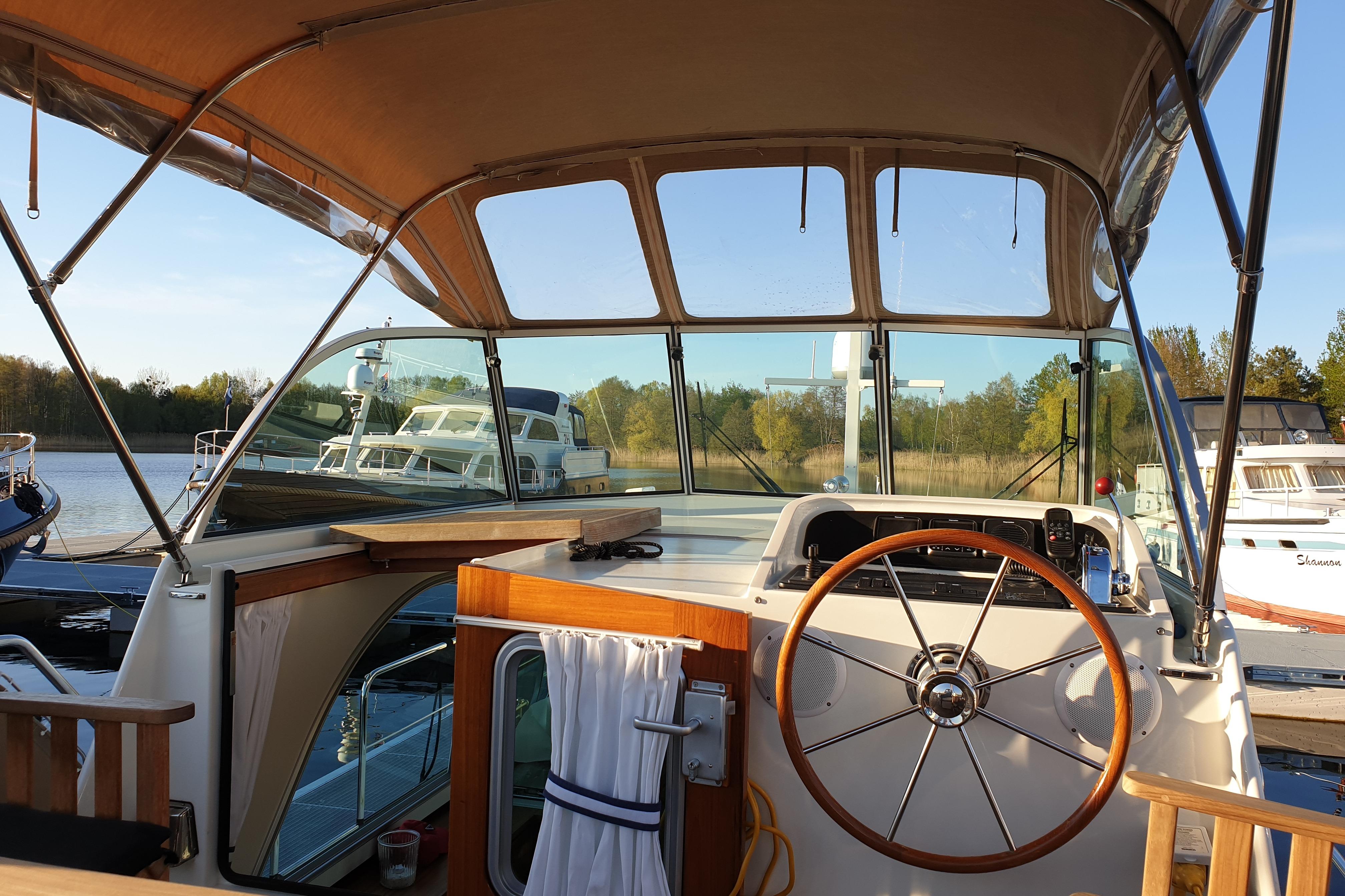 Cockpit view of 2014 Linssen Yachts The New Classic Sturdy 36 AC, docked by a serene lake.