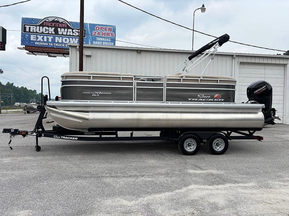 2025 Sun Tracker Party Barge 20 DLX pontoon boat on trailer, parked near a truck wash.