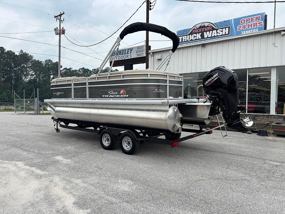 2025 Sun Tracker Party Barge 20 DLX pontoon boat on trailer, parked near a truck wash.
