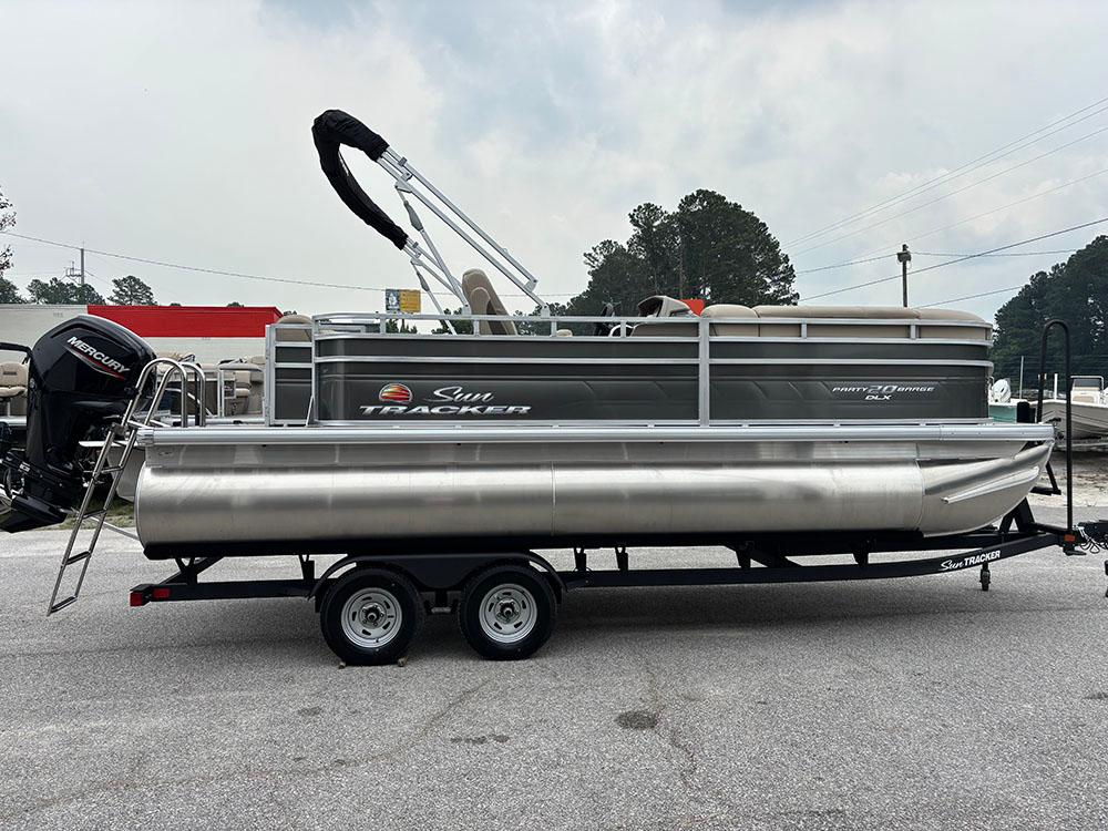 2025 Sun Tracker Party Barge 20 DLX pontoon boat on trailer, parked outdoors.