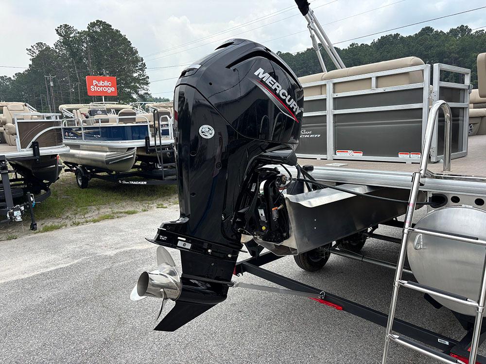 2025 Sun Tracker Party Barge 20 DLX with Mercury outboard motor, parked near storage facility.