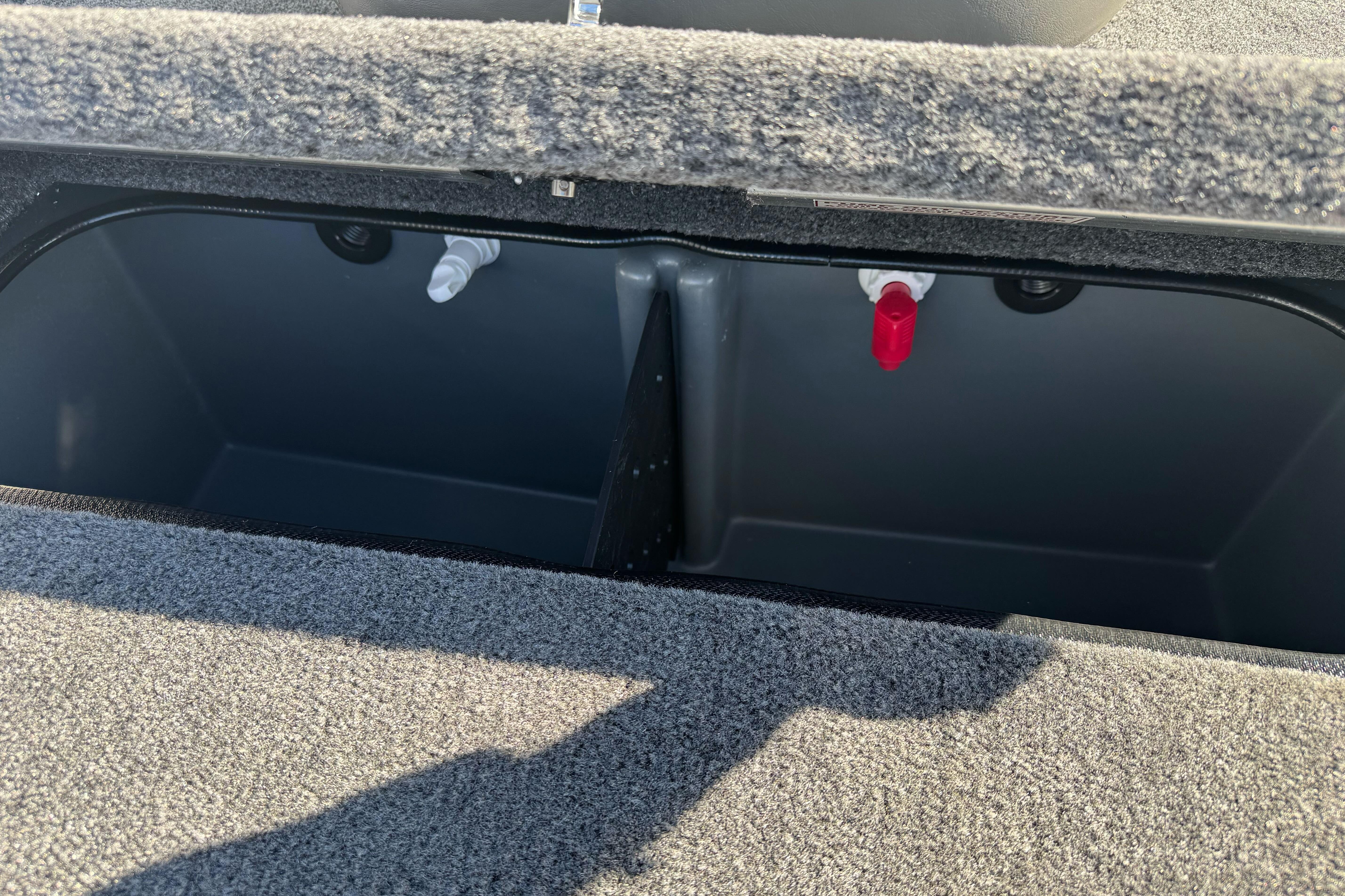 Open storage compartment in 2026 Ranger RT188P boat, featuring carpeted interior and dual valves.