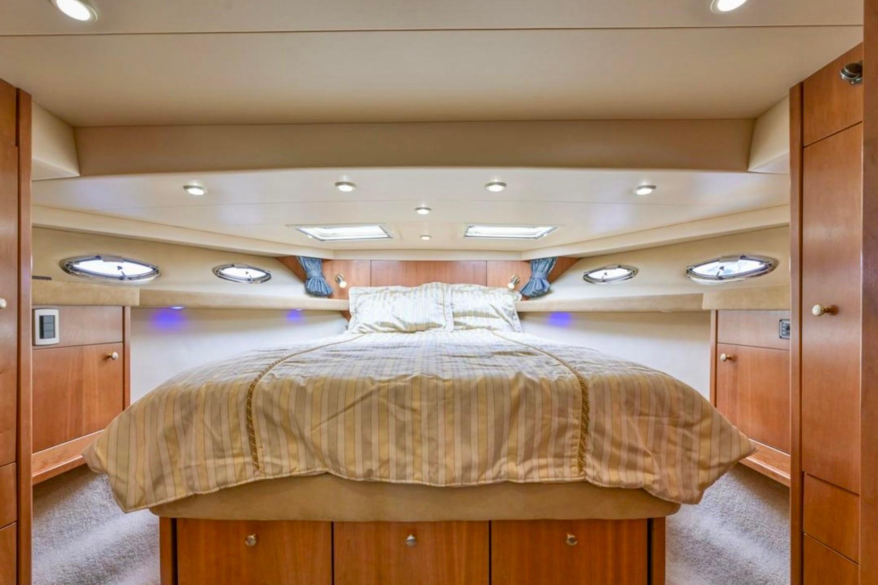 Luxurious bedroom interior of 2004 Meridian 490 Pilothouse yacht with elegant wood finish.