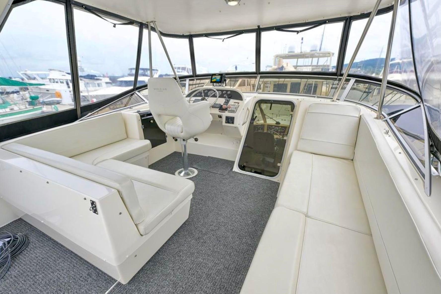 2004 Meridian 490 Pilothouse interior with white seating and helm, docked at marina.