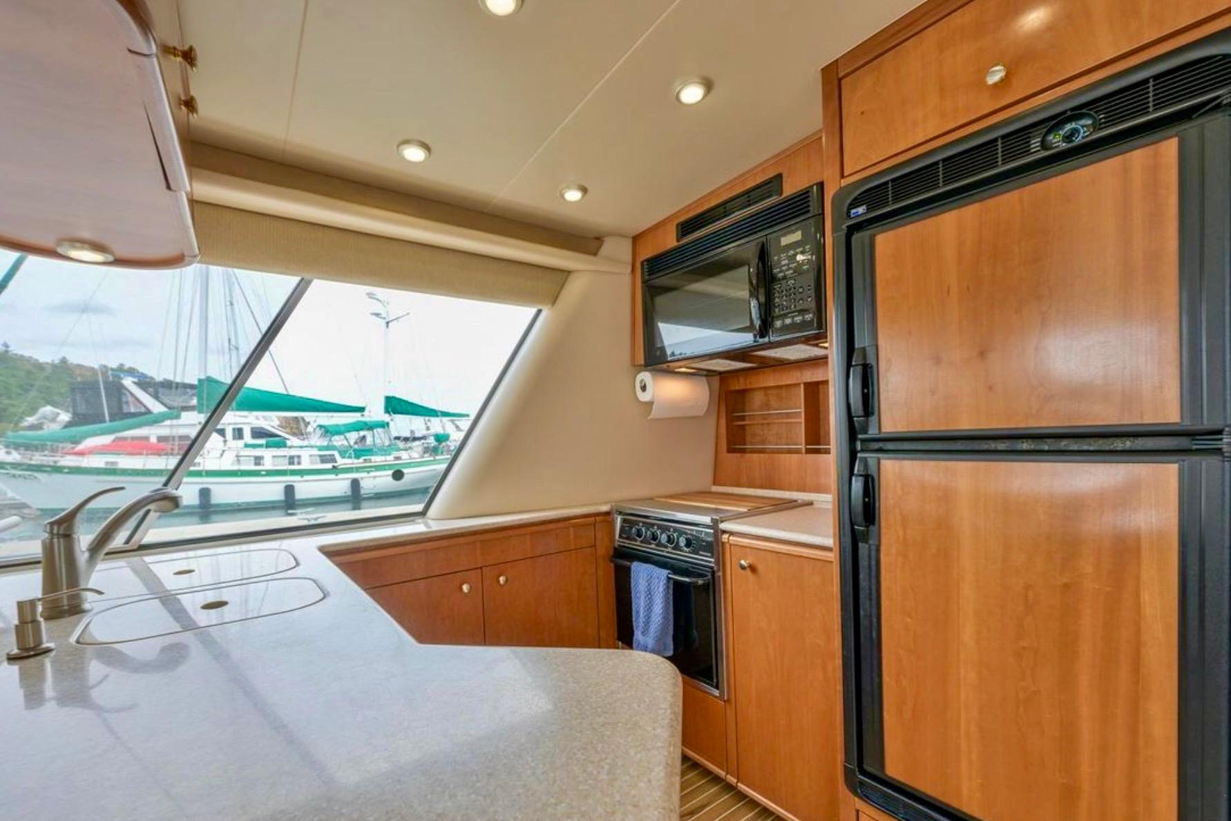2004 Meridian 490 Pilothouse kitchen with wood cabinetry, appliances, and marina view.