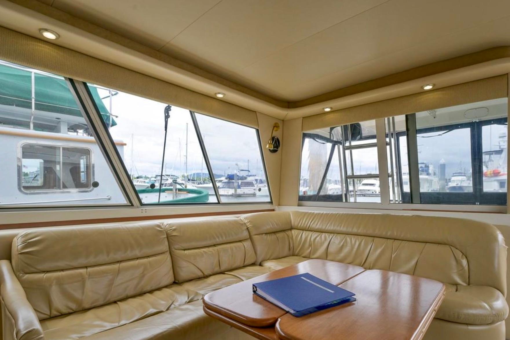 Luxurious interior of 2004 Meridian 490 Pilothouse yacht with leather seating and marina view.