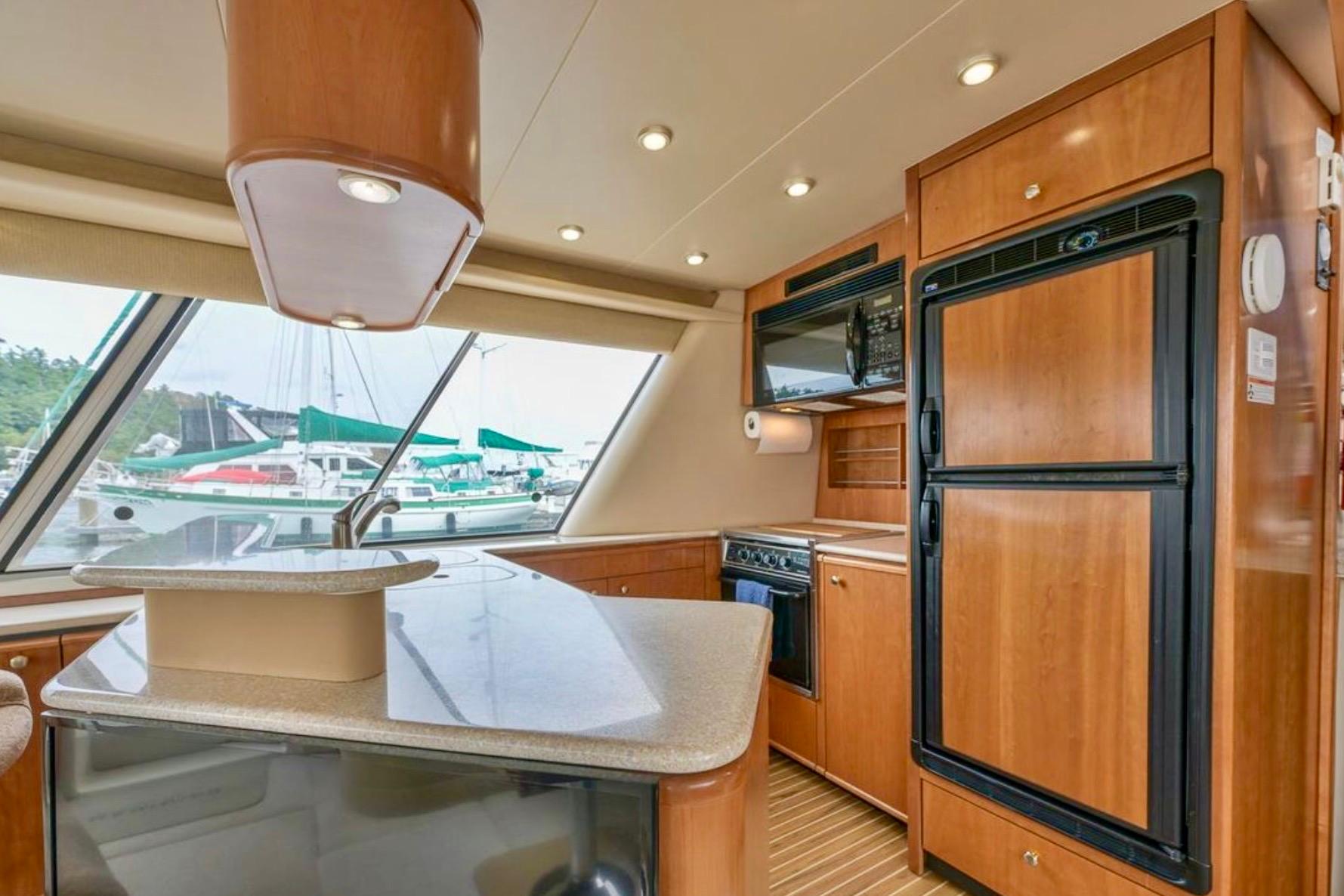 2004 Meridian 490 Pilothouse kitchen interior with wood cabinetry and modern appliances.