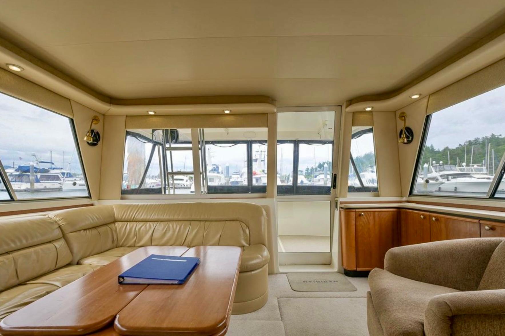 Luxurious interior of 2004 Meridian 490 Pilothouse yacht with leather seating and panoramic windows.