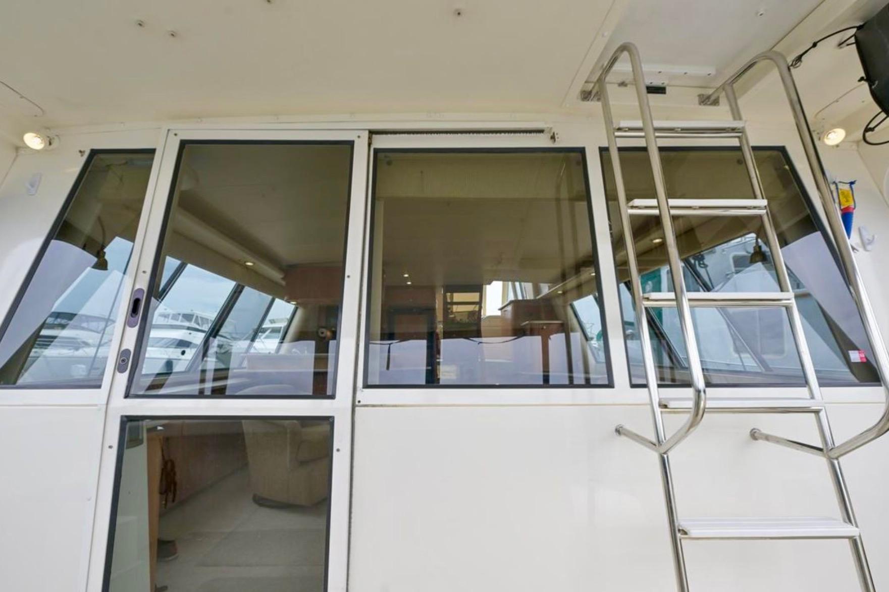2004 Meridian 490 Pilothouse yacht with glass doors and ladder, showcasing interior.