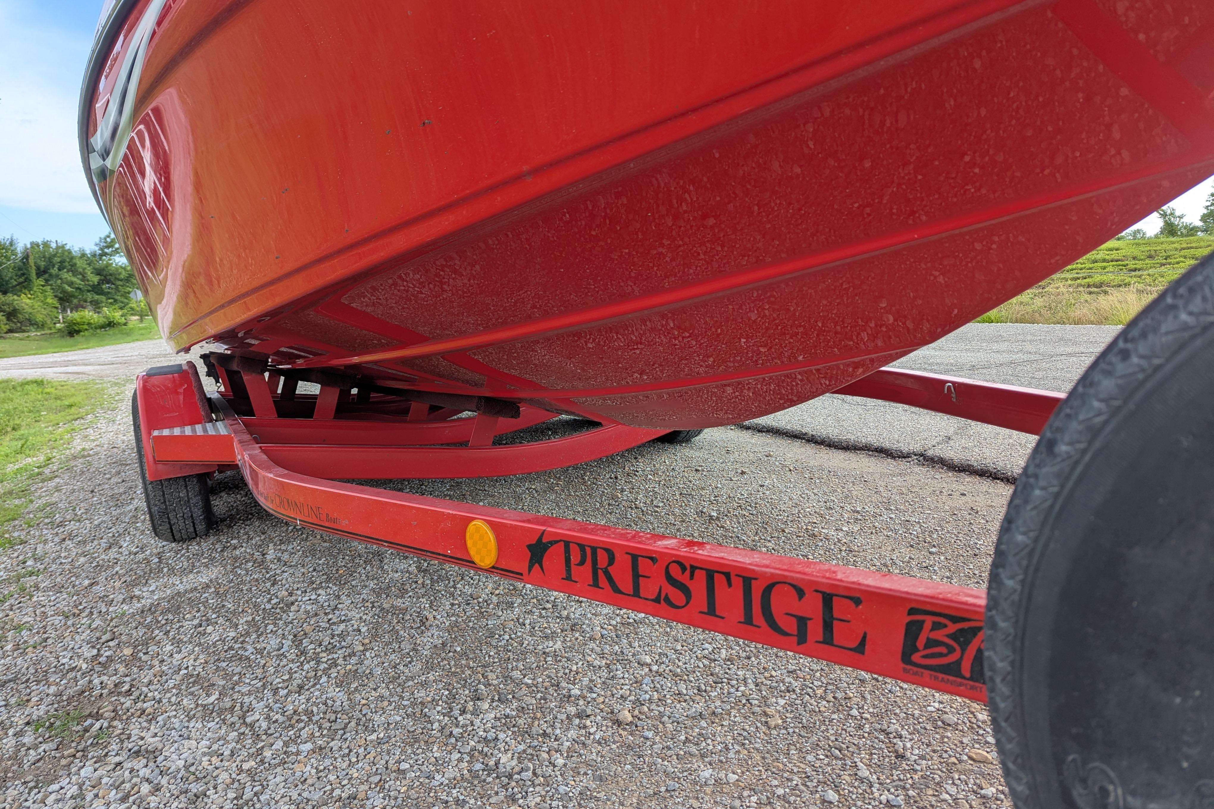 Red 2004 Crownline 225 BR boat on Prestige trailer, parked on gravel.