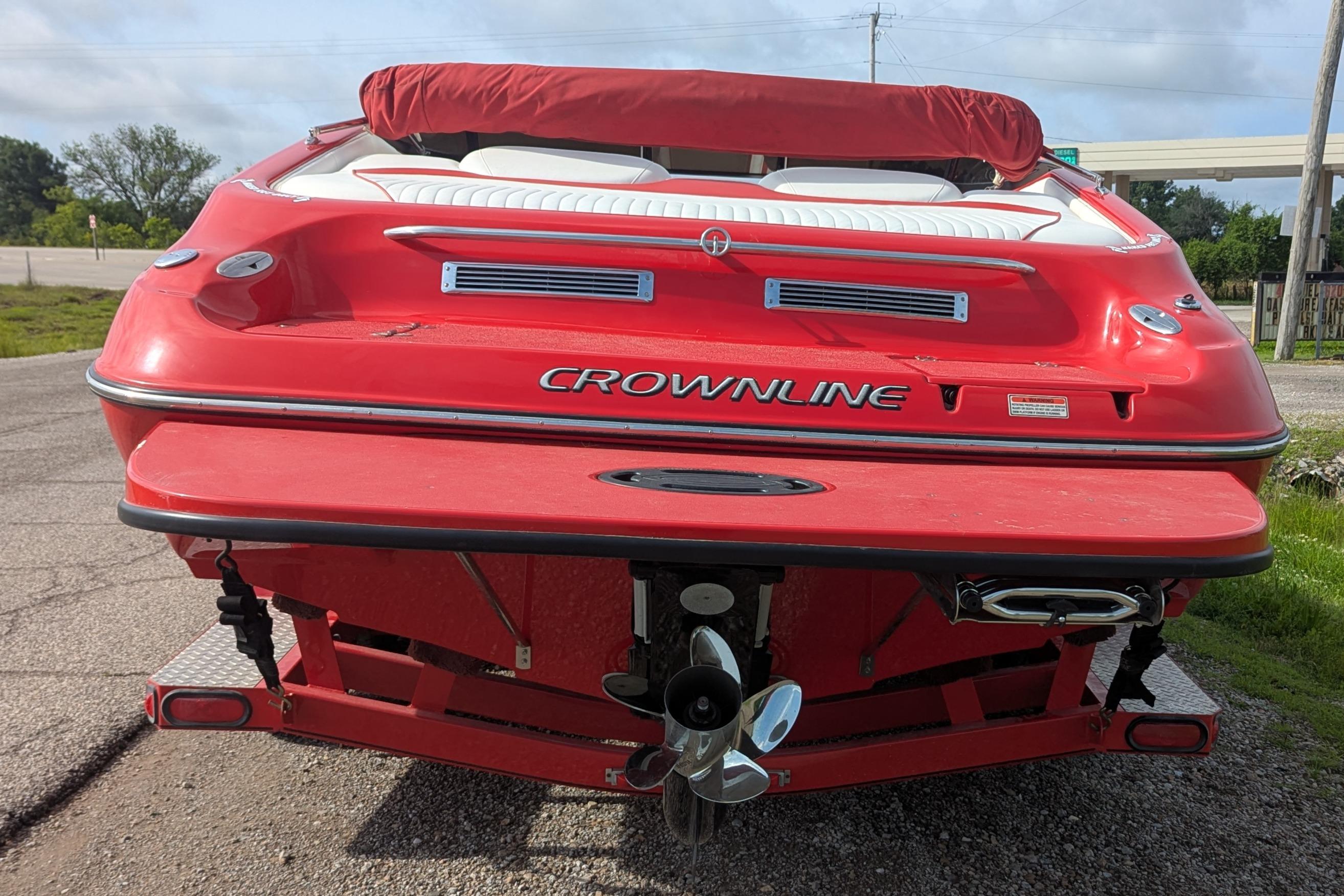 Red 2004 Crownline 225 BR boat on trailer, rear view, parked outdoors.