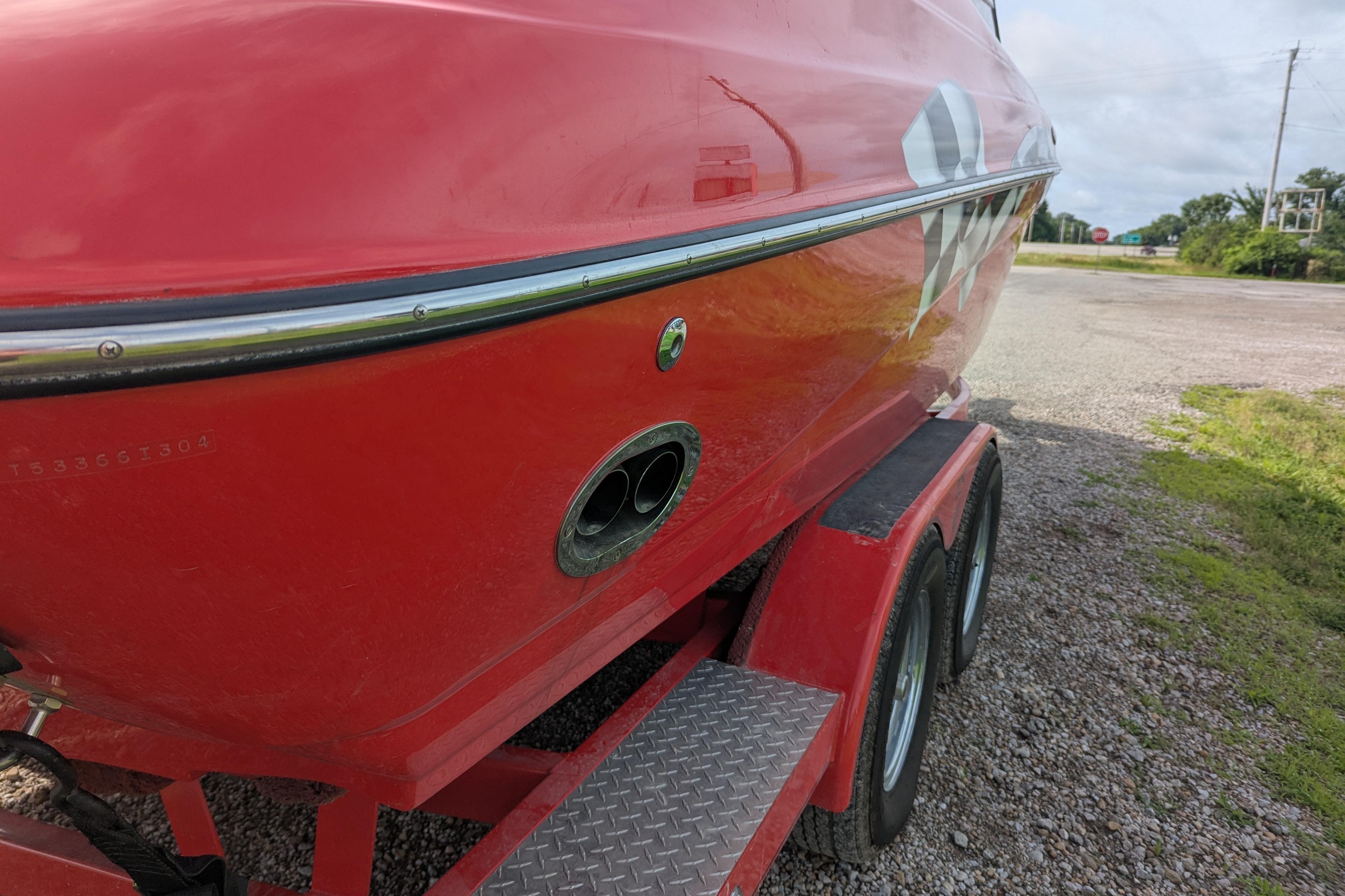 Red 2004 Crownline 225 BR boat on trailer, parked on gravel road.