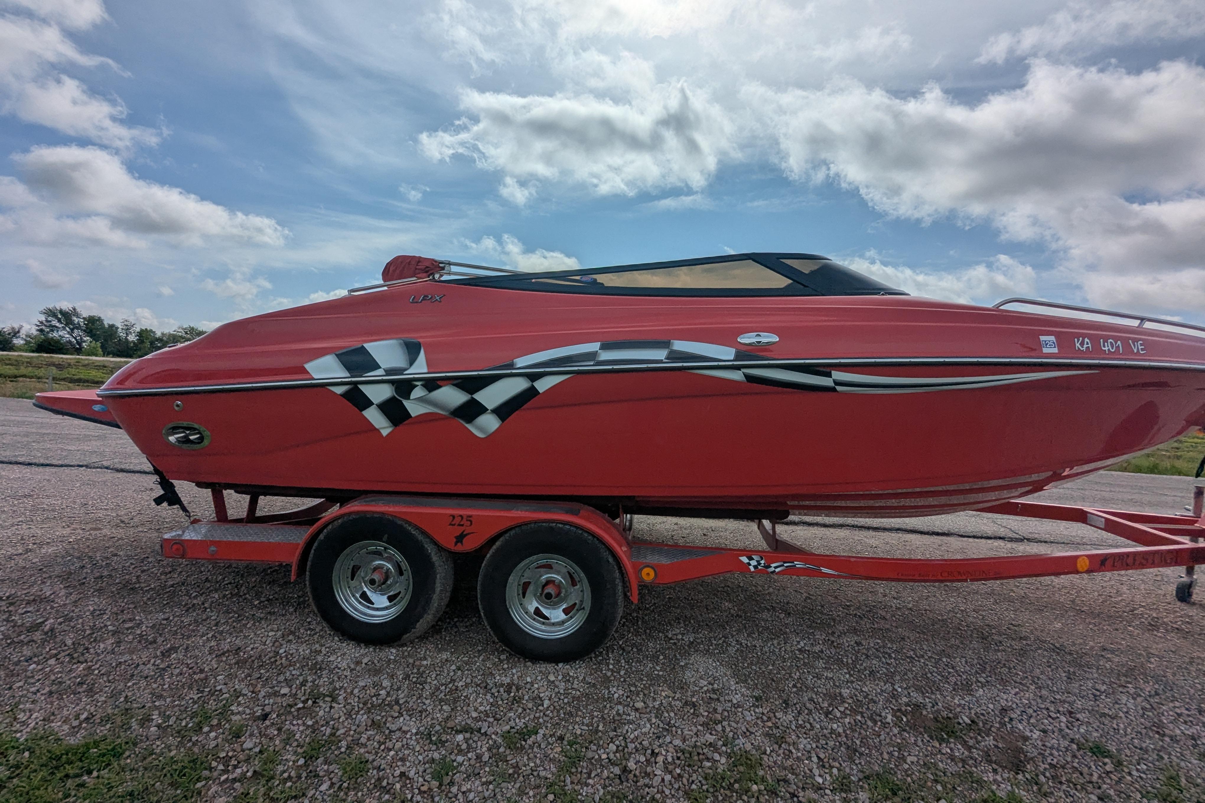 Red 2004 Crownline 225 BR boat on trailer under cloudy sky.