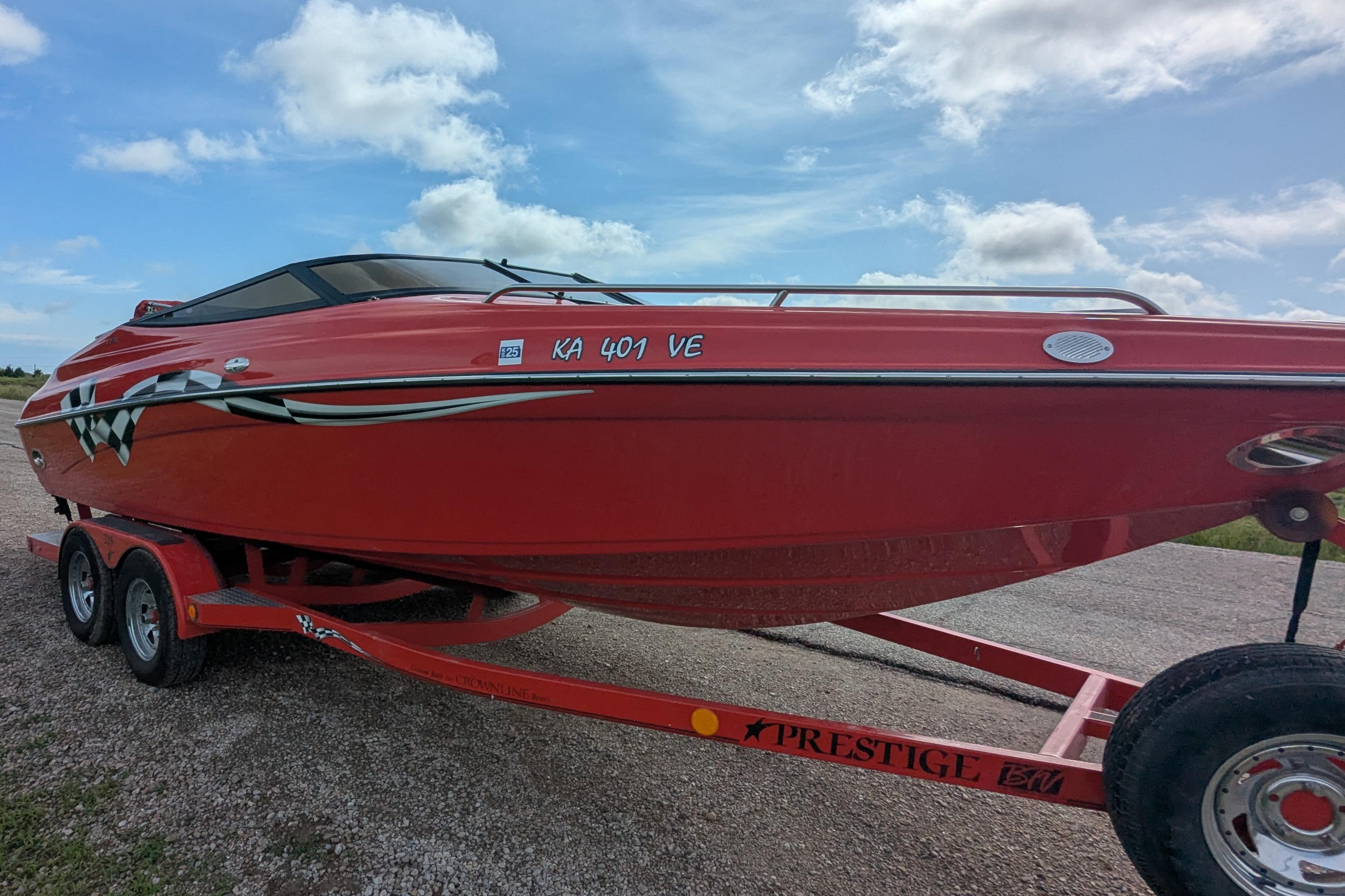Red 2004 Crownline 225 BR boat on trailer under blue sky.
