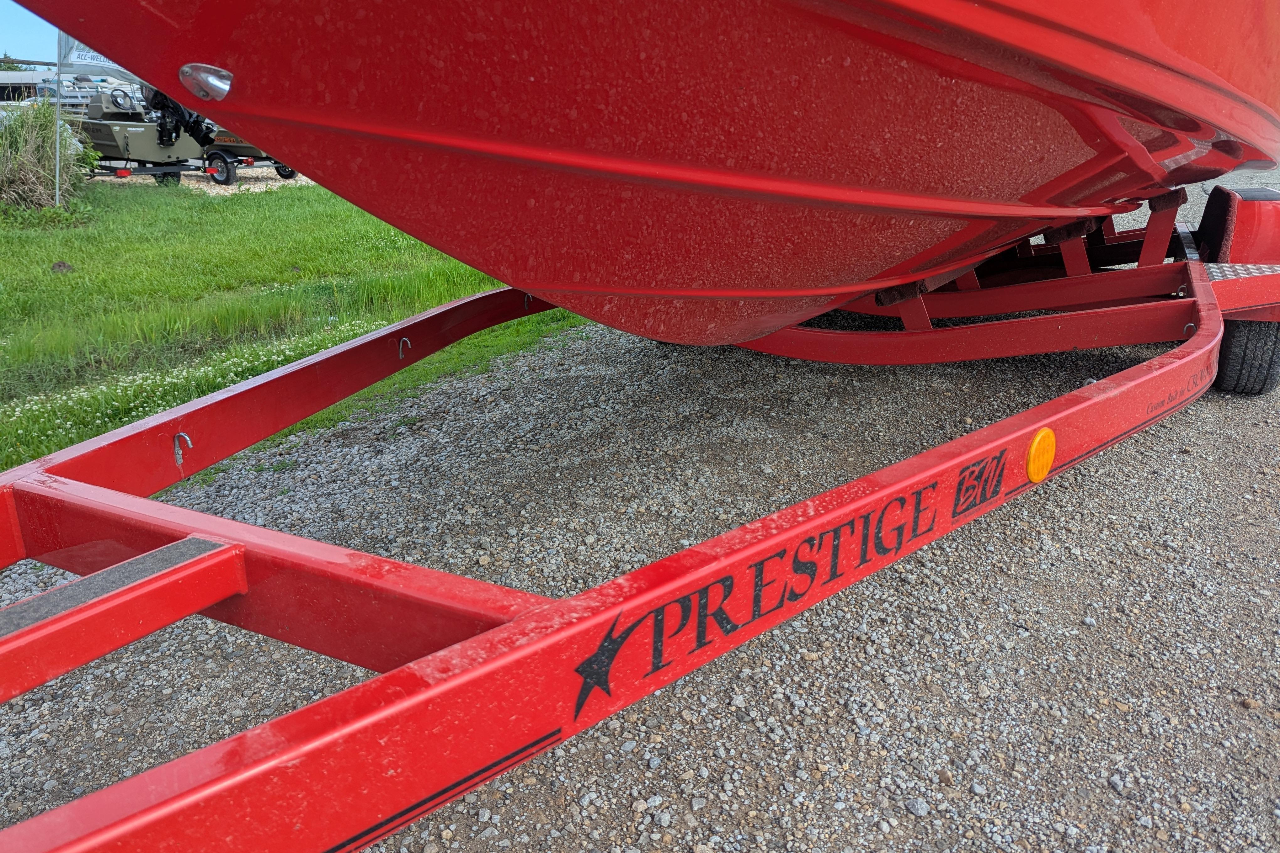 Red 2004 Crownline 225 BR boat on Prestige trailer, parked on gravel.