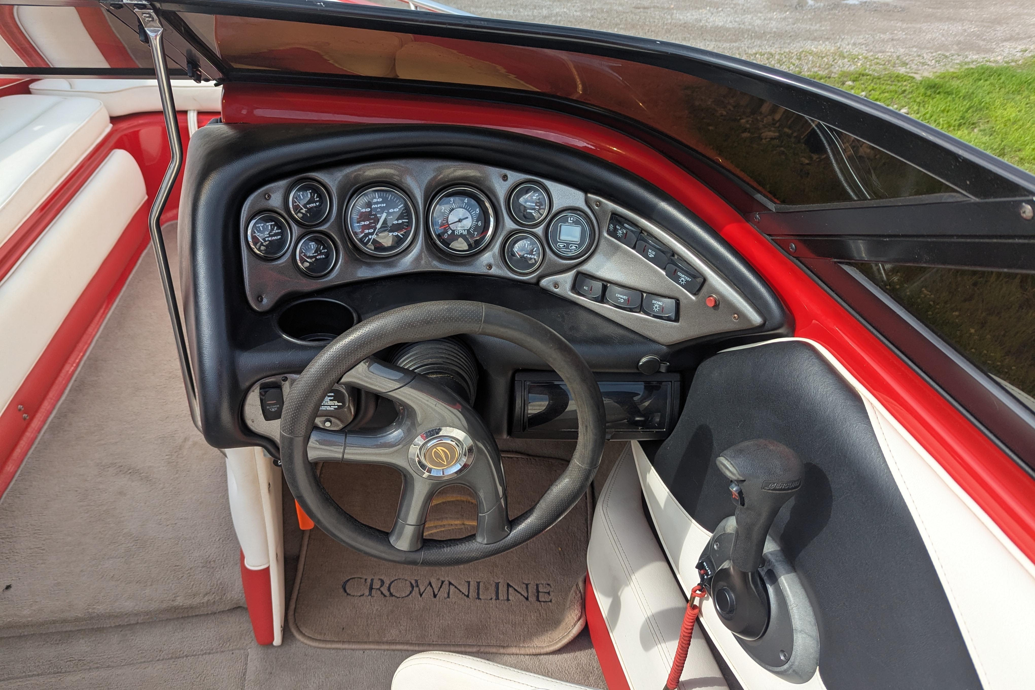 2004 Crownline 225 BR boat dashboard with steering wheel and gauges, featuring red and white interior.