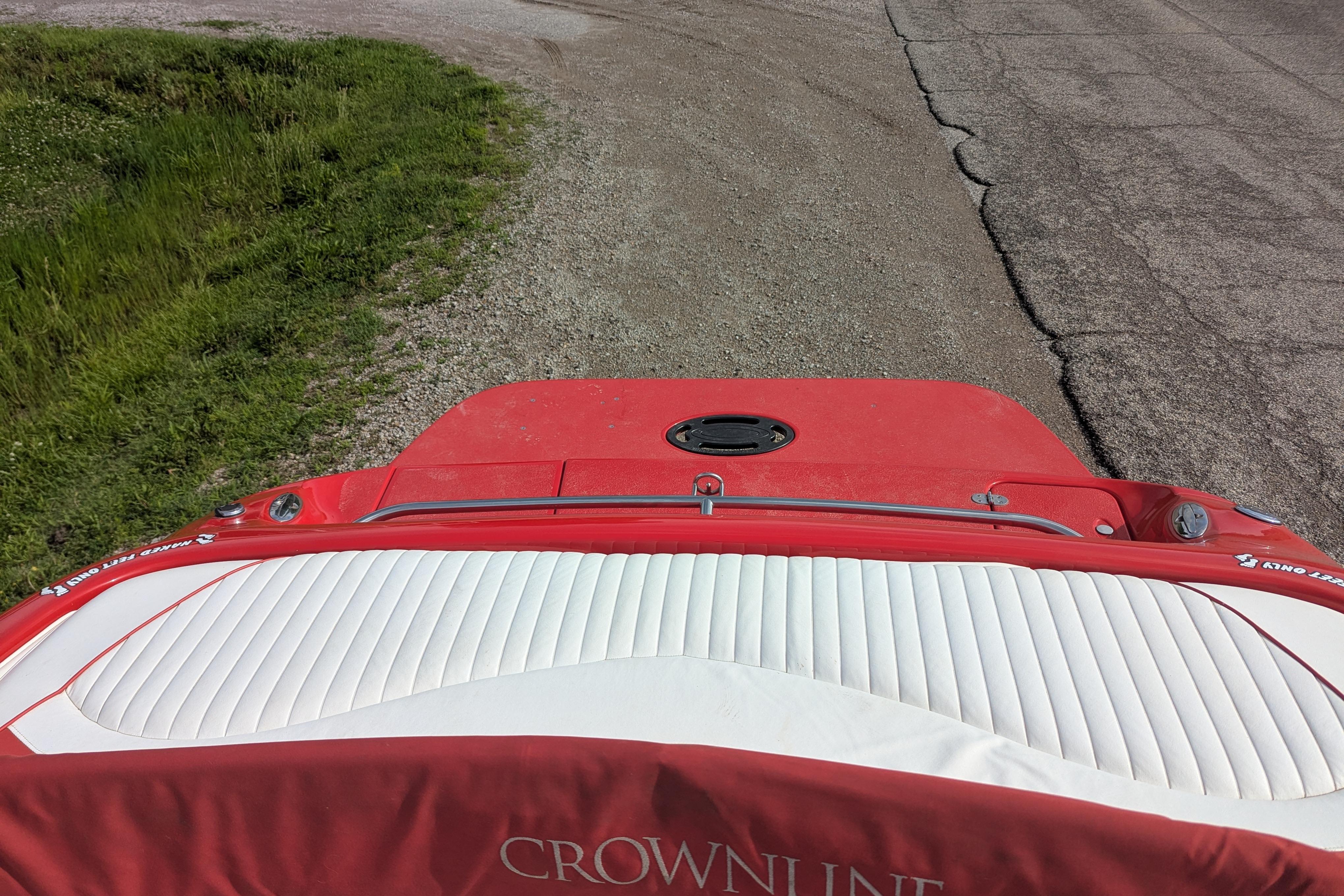 Red and white 2004 Crownline 225 BR boat on gravel road.